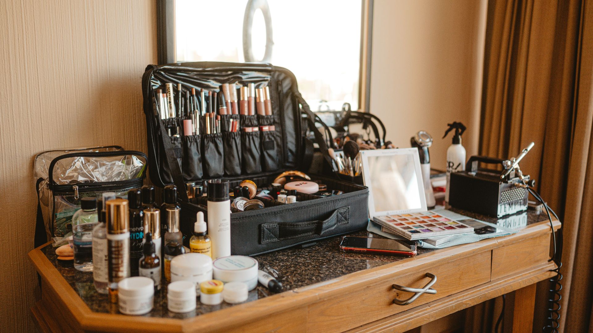 Makeup artist's kit spread across a wooden vanity table.
