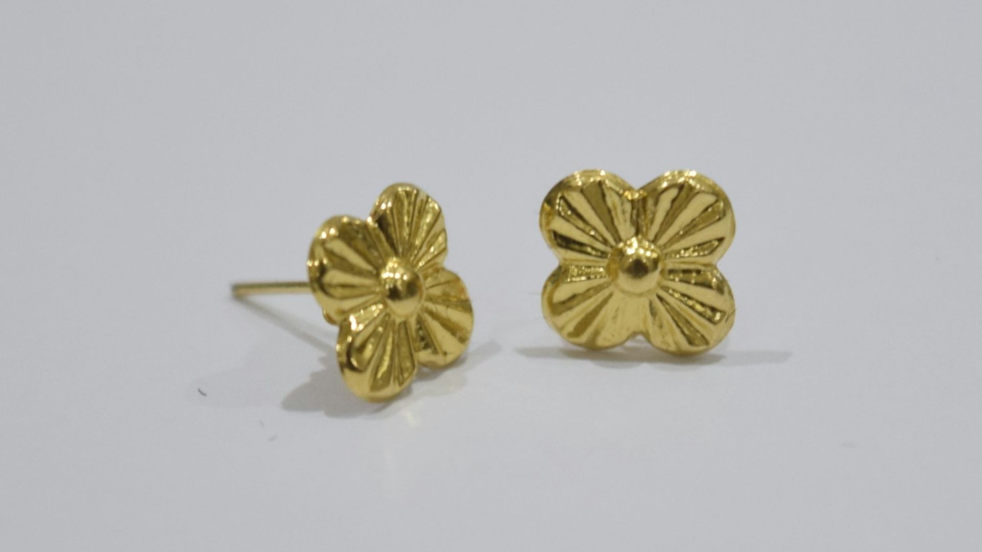 Two gold stud earrings with floral design