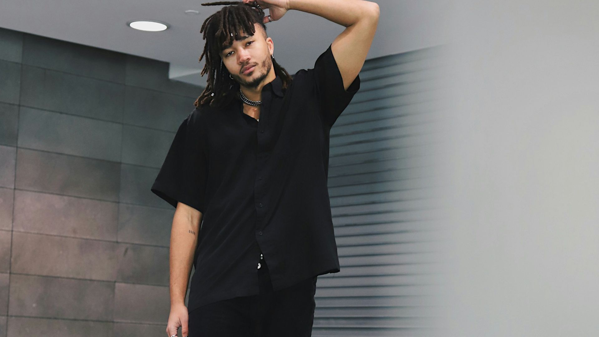 woman in black crew neck t-shirt and black pants standing beside gray wall