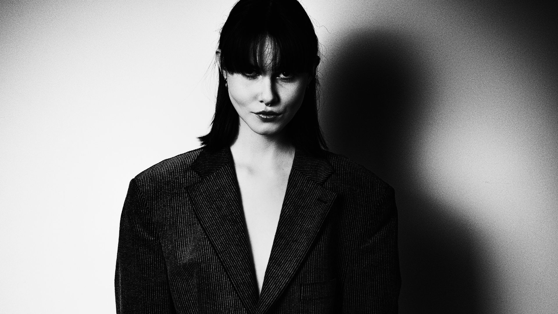 Woman in oversized blazer against a spotlighted wall