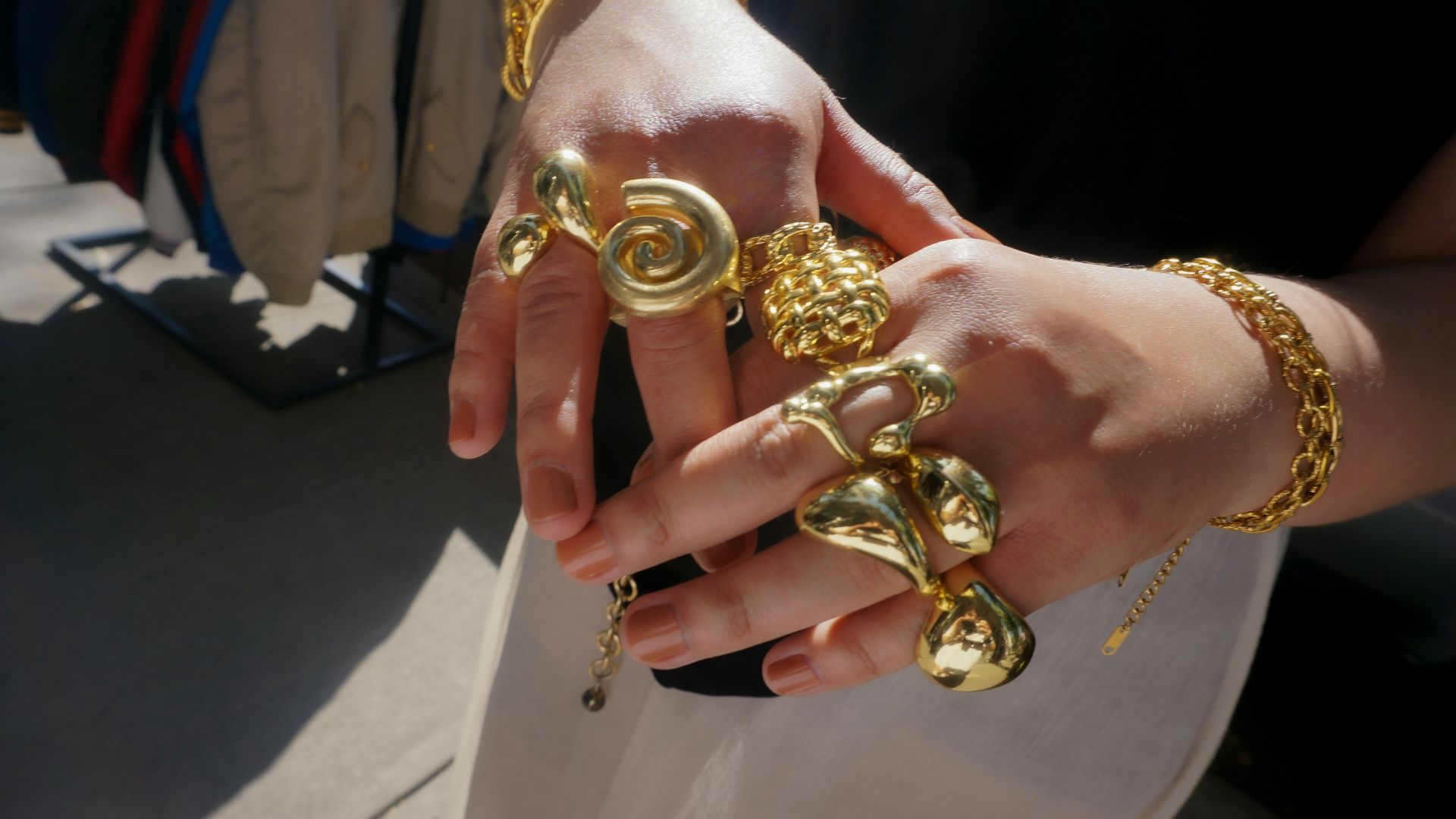 Hands adorned with chunky gold rings and bracelets.
