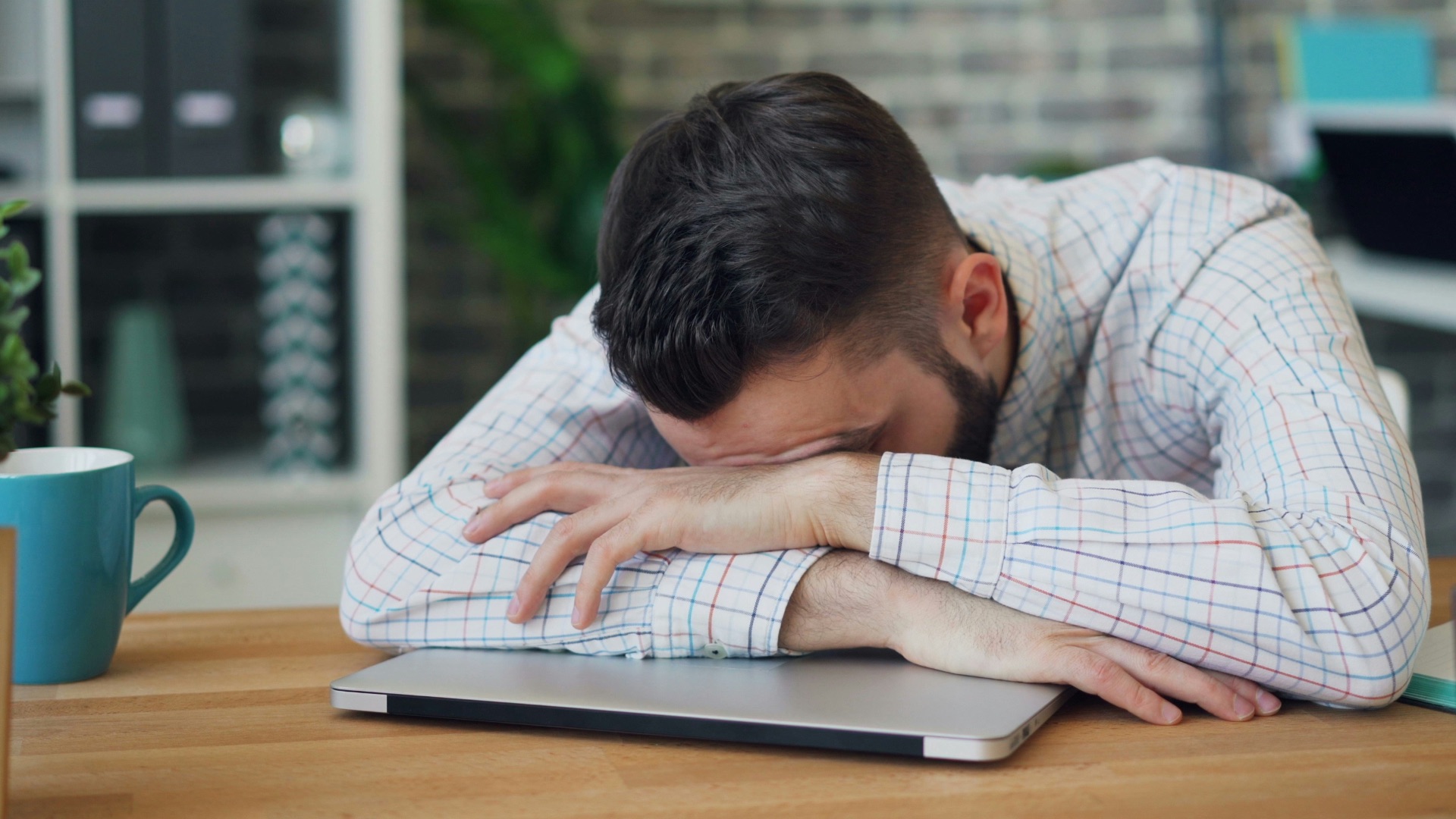 a man sitting at a desk with his head in his hands