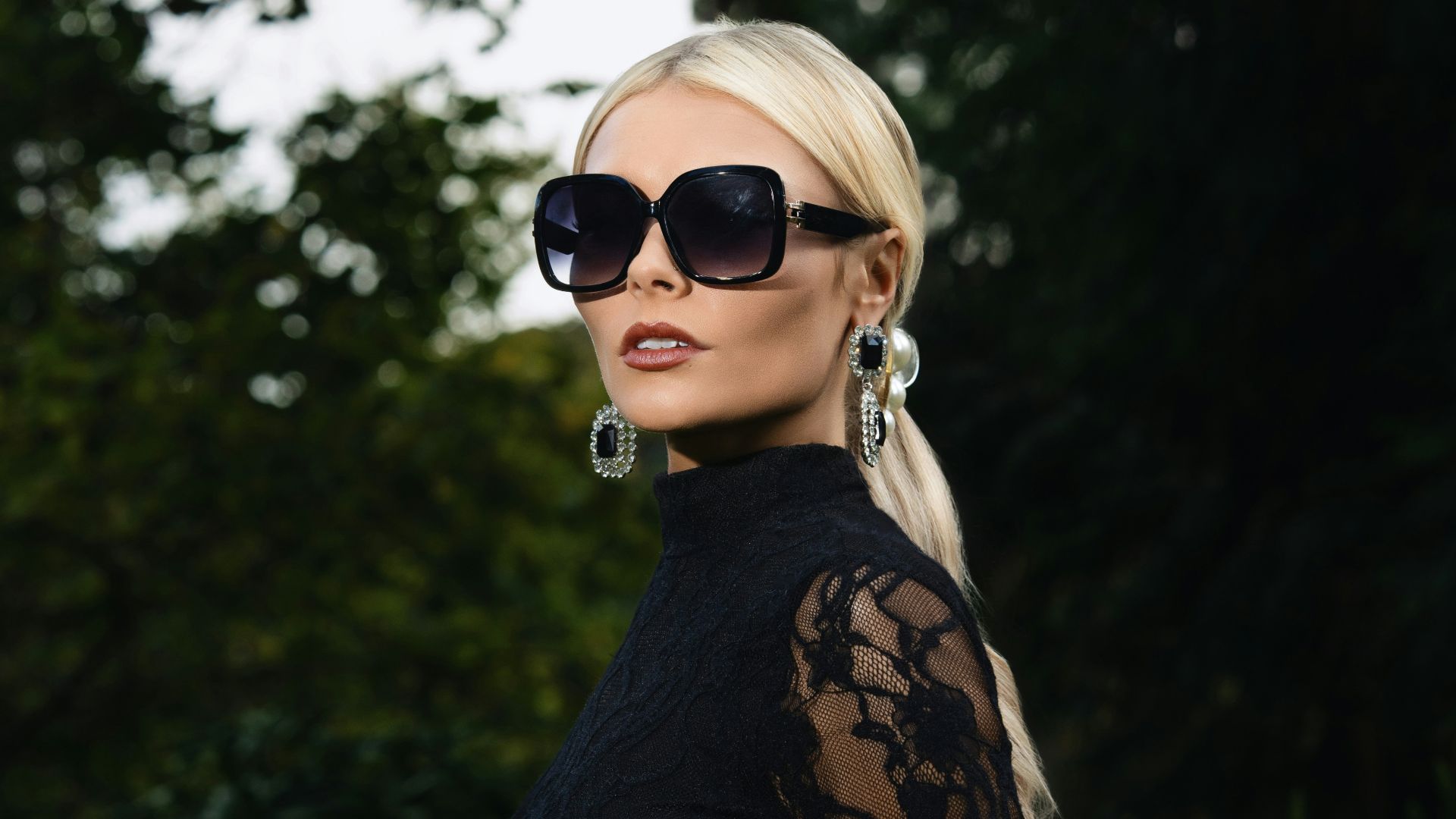 Woman in black lace dress and sunglasses outdoors