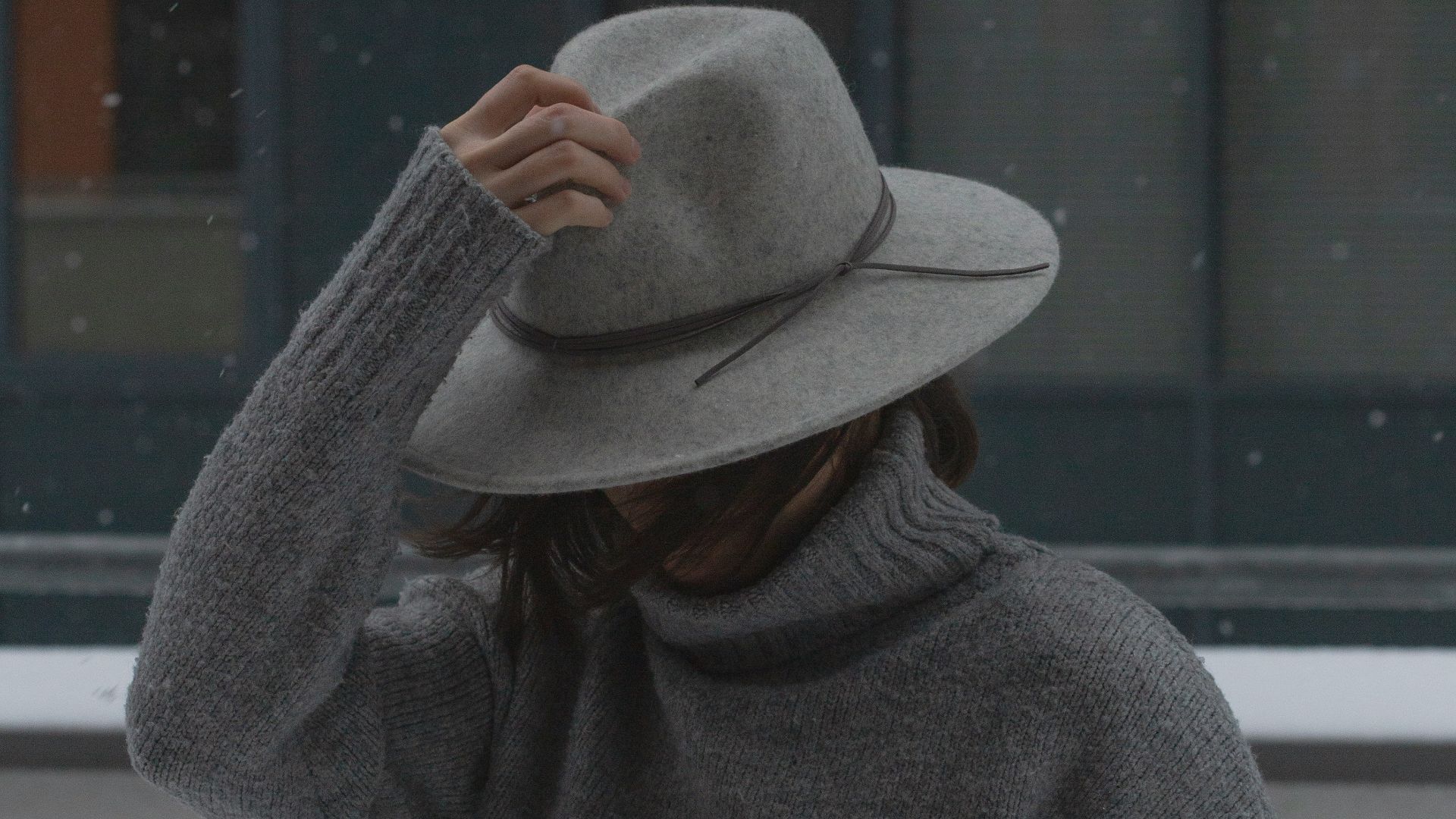 man in gray sweater wearing brown fedora hat