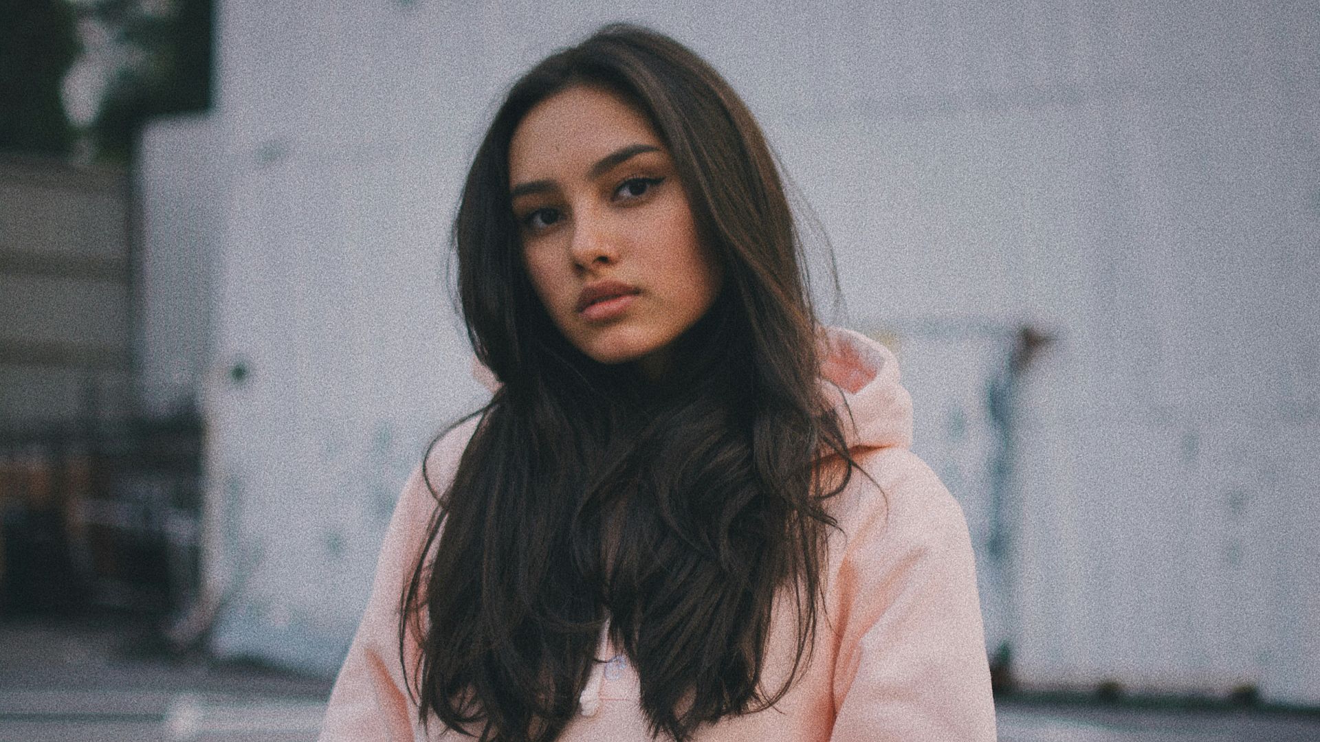 woman wearing pink pullover hoodie standing near wall
