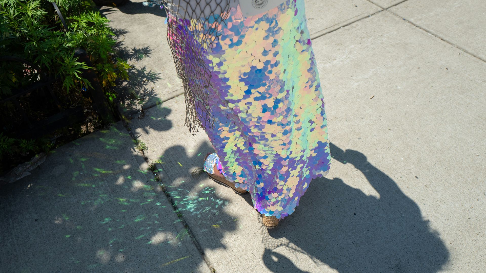 Person in iridescent sequined skirt walking on sidewalk
