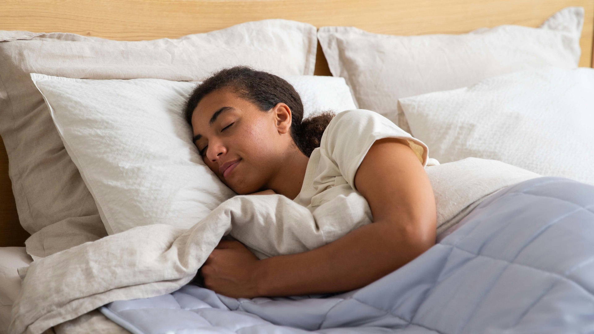 a young girl sleeping in a bed with white sheets