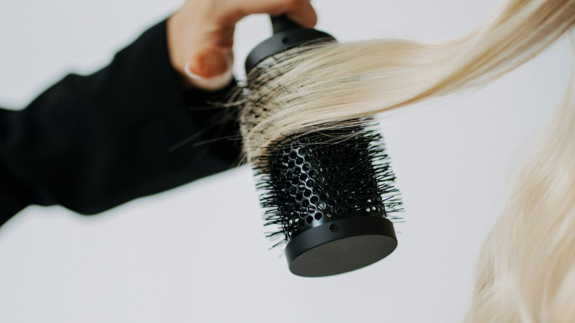 A woman blow drying her hair with a hair dryer