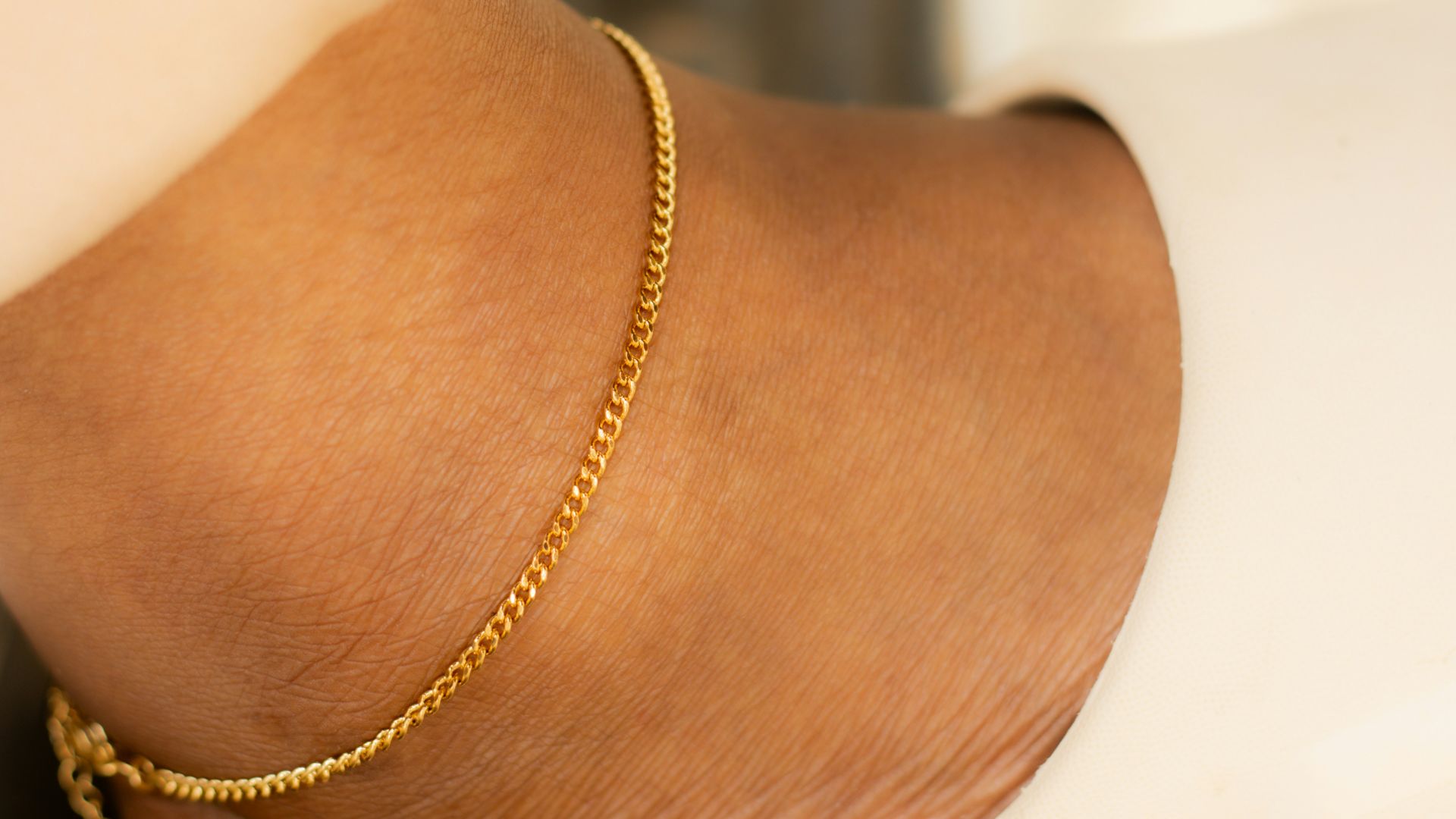 Ankle with a gold bracelet and a slipper.