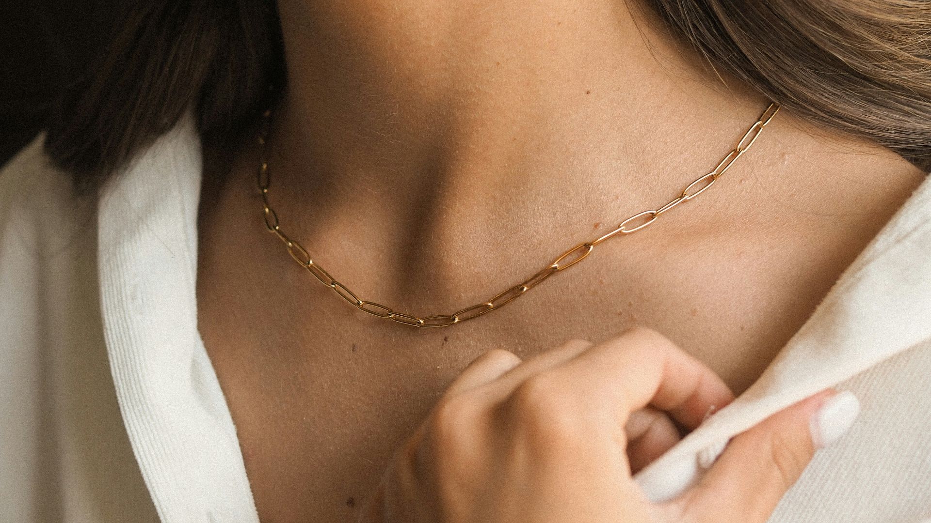 a woman wearing a white shirt and a gold necklace