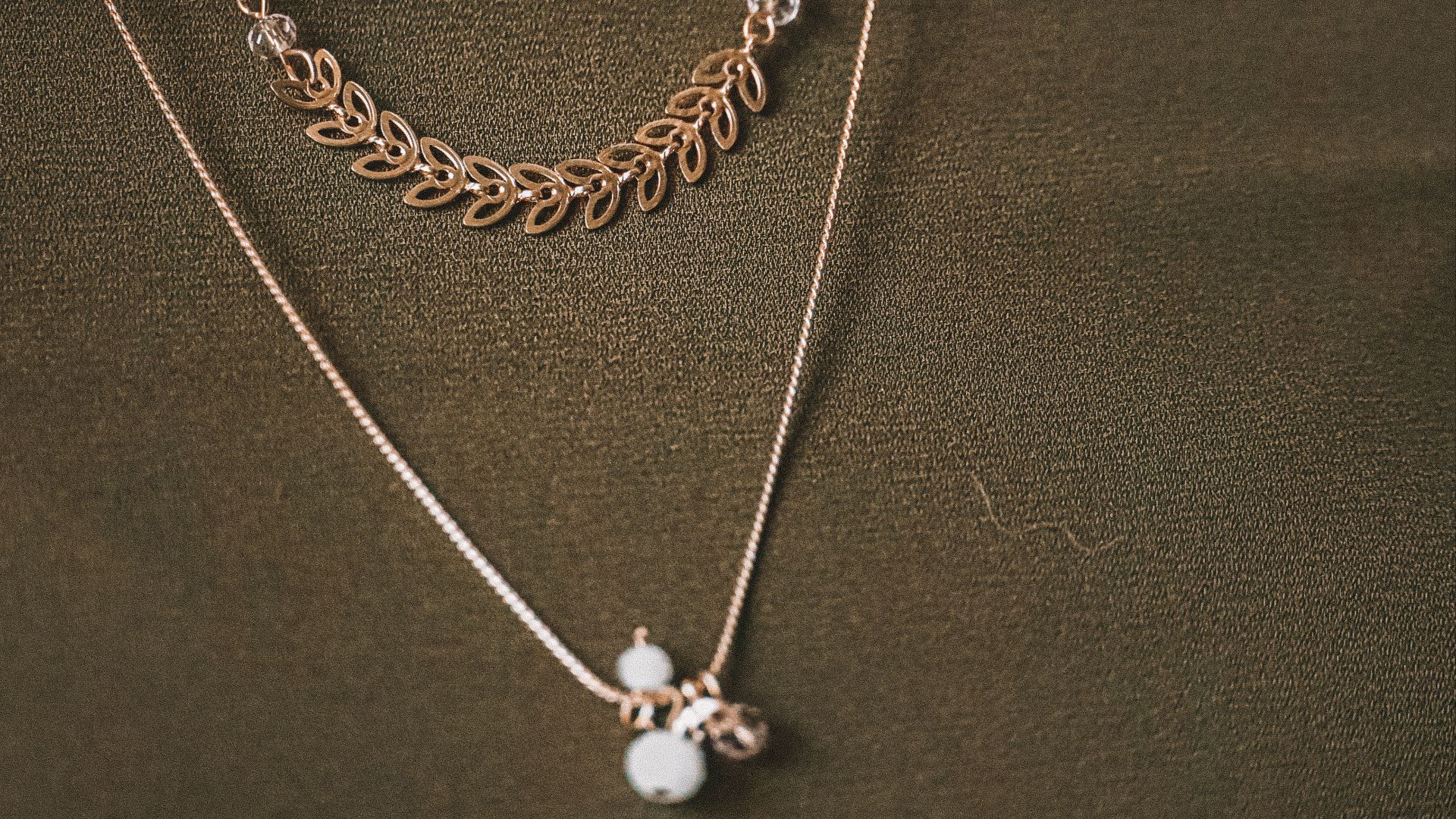 person wearing silver necklace with silver pendant