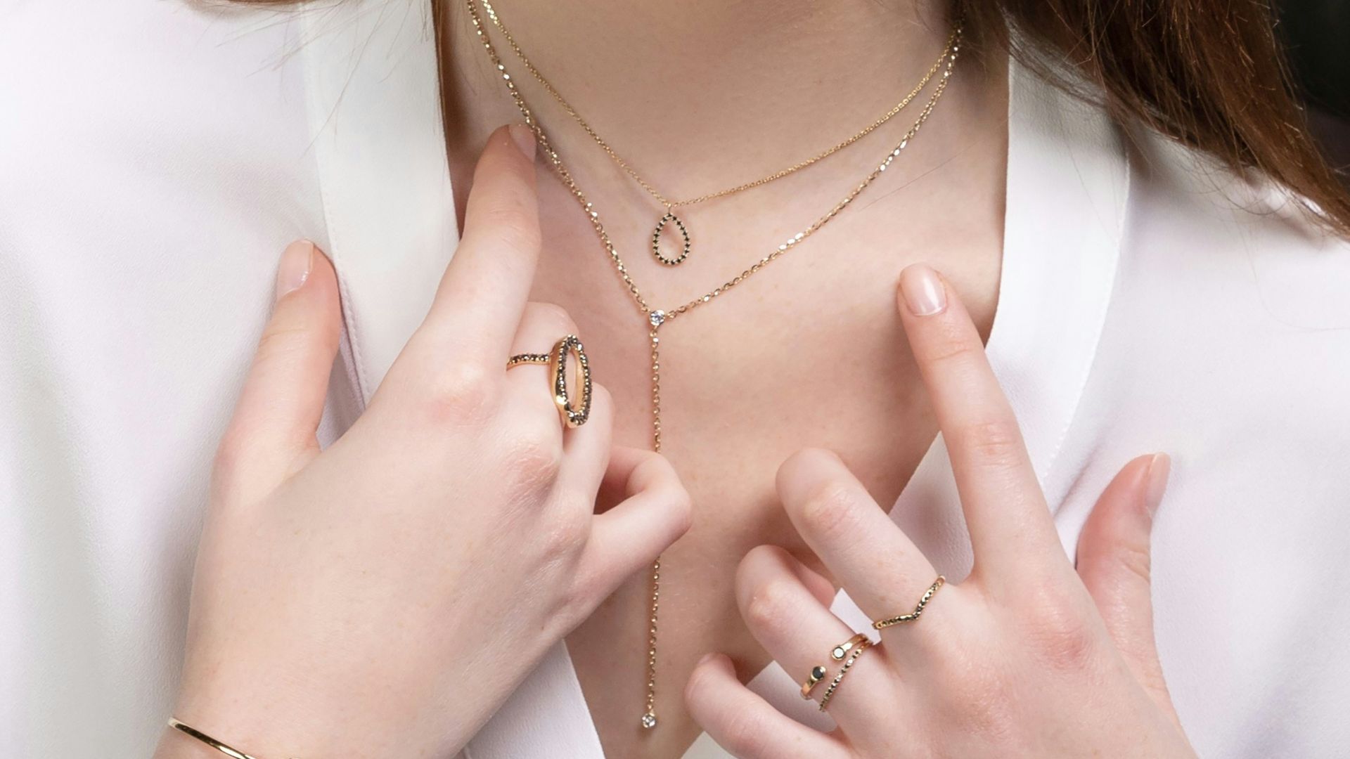 a close up of a person wearing rings and a necklace