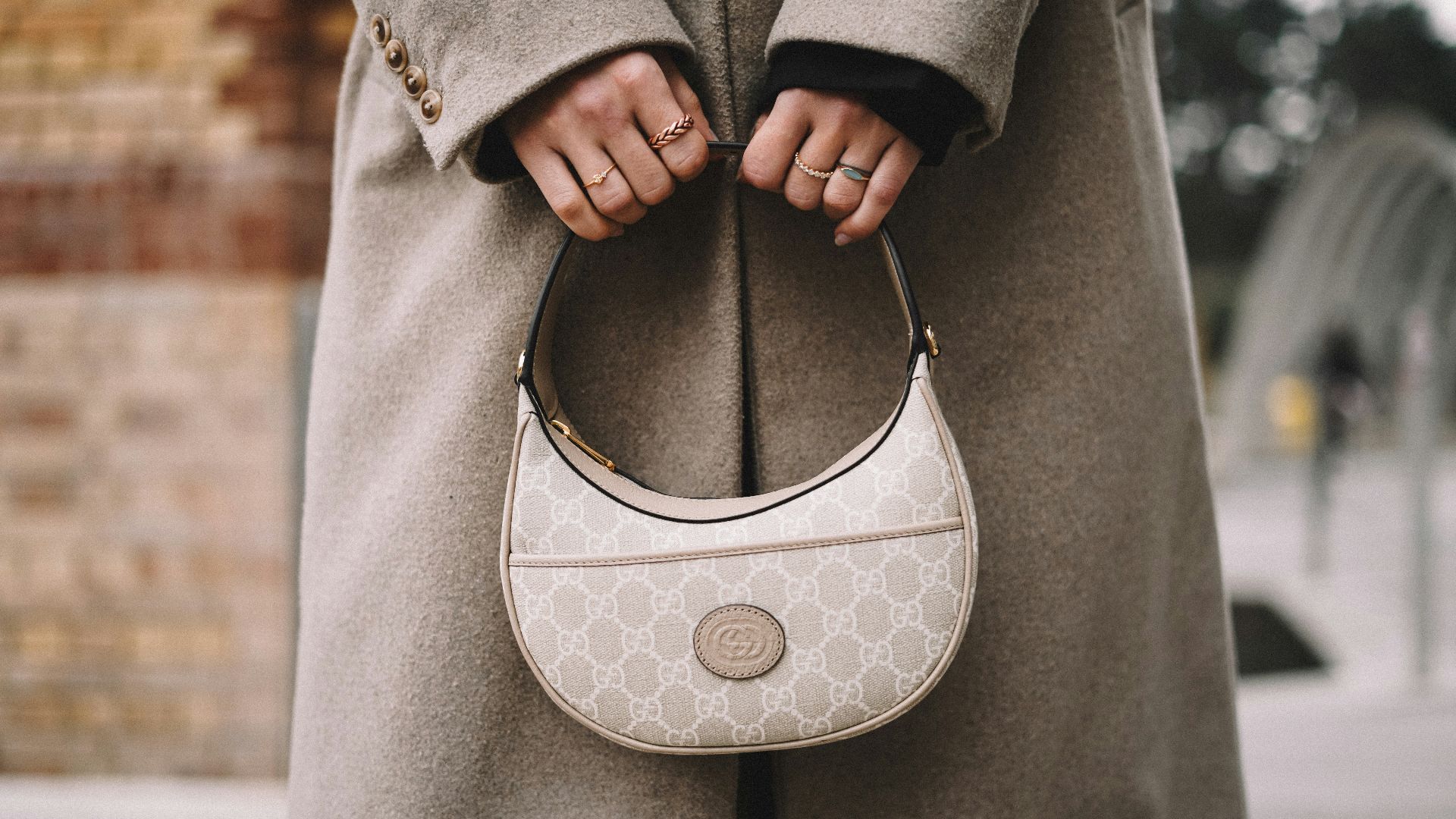 a woman in a coat holding a white purse