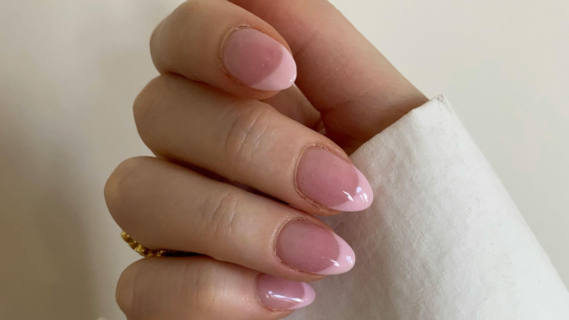 person with pink manicure on white textile