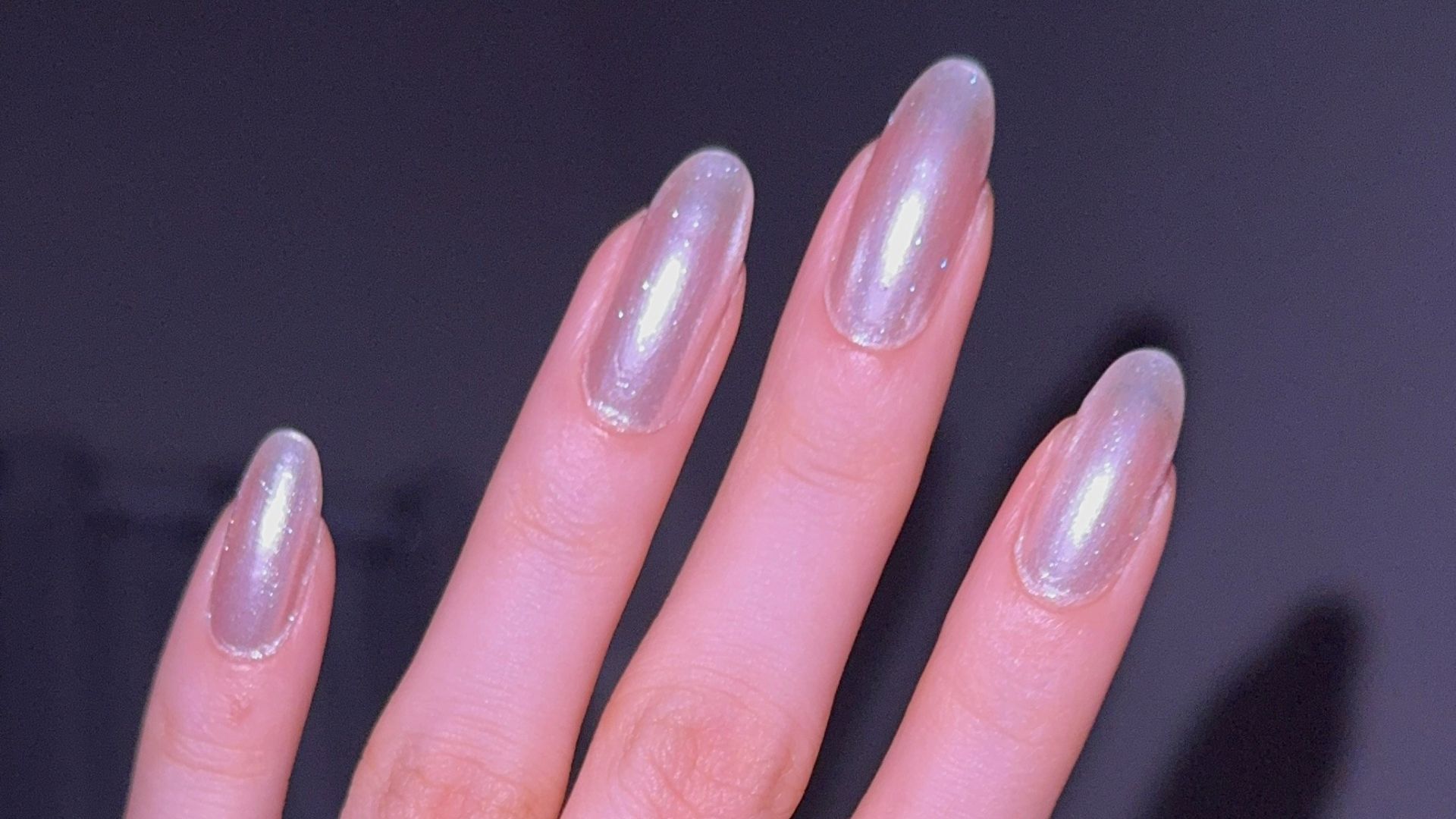 Hand with pearlescent nails and rings.