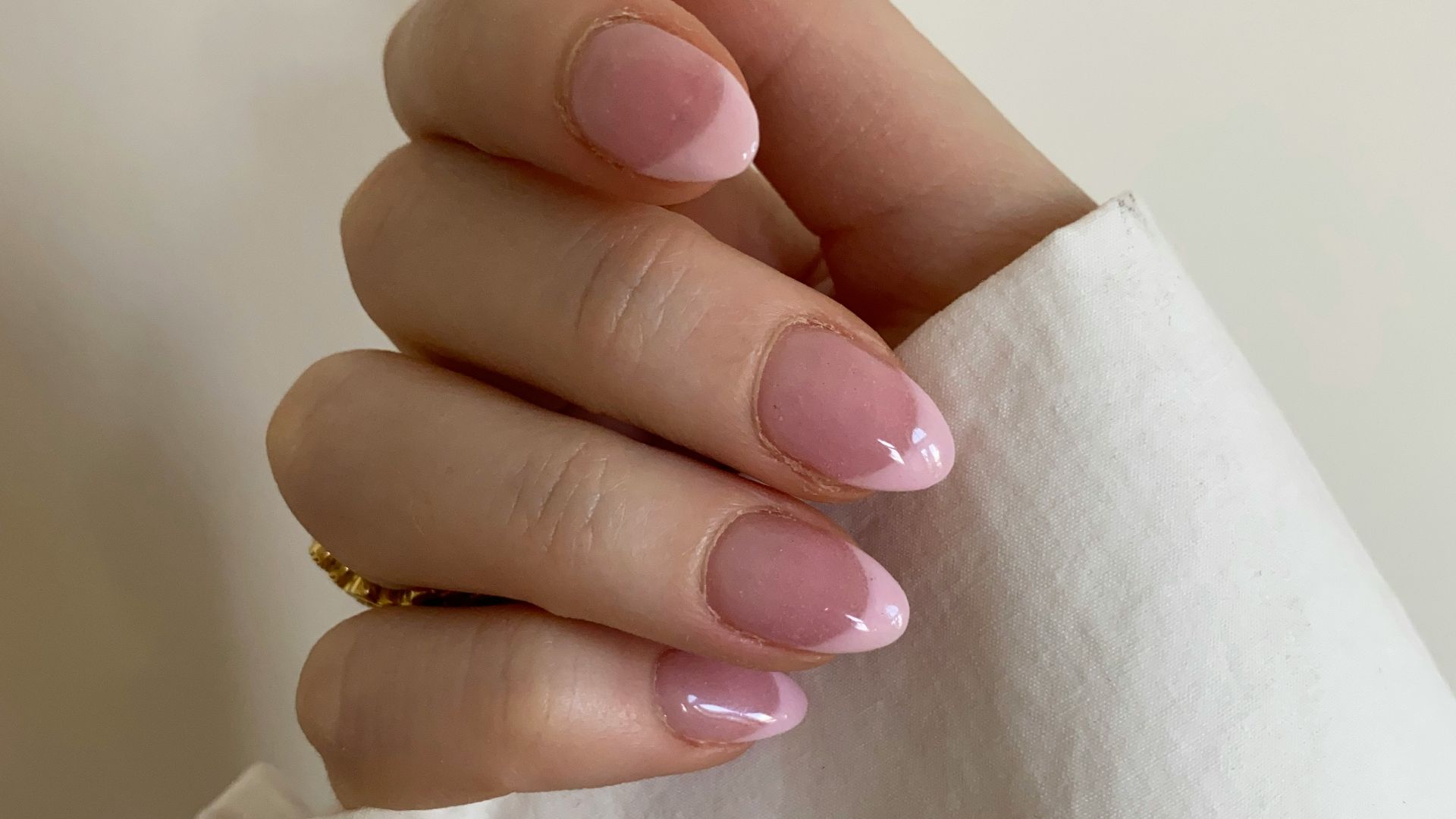 person with pink manicure on white textile