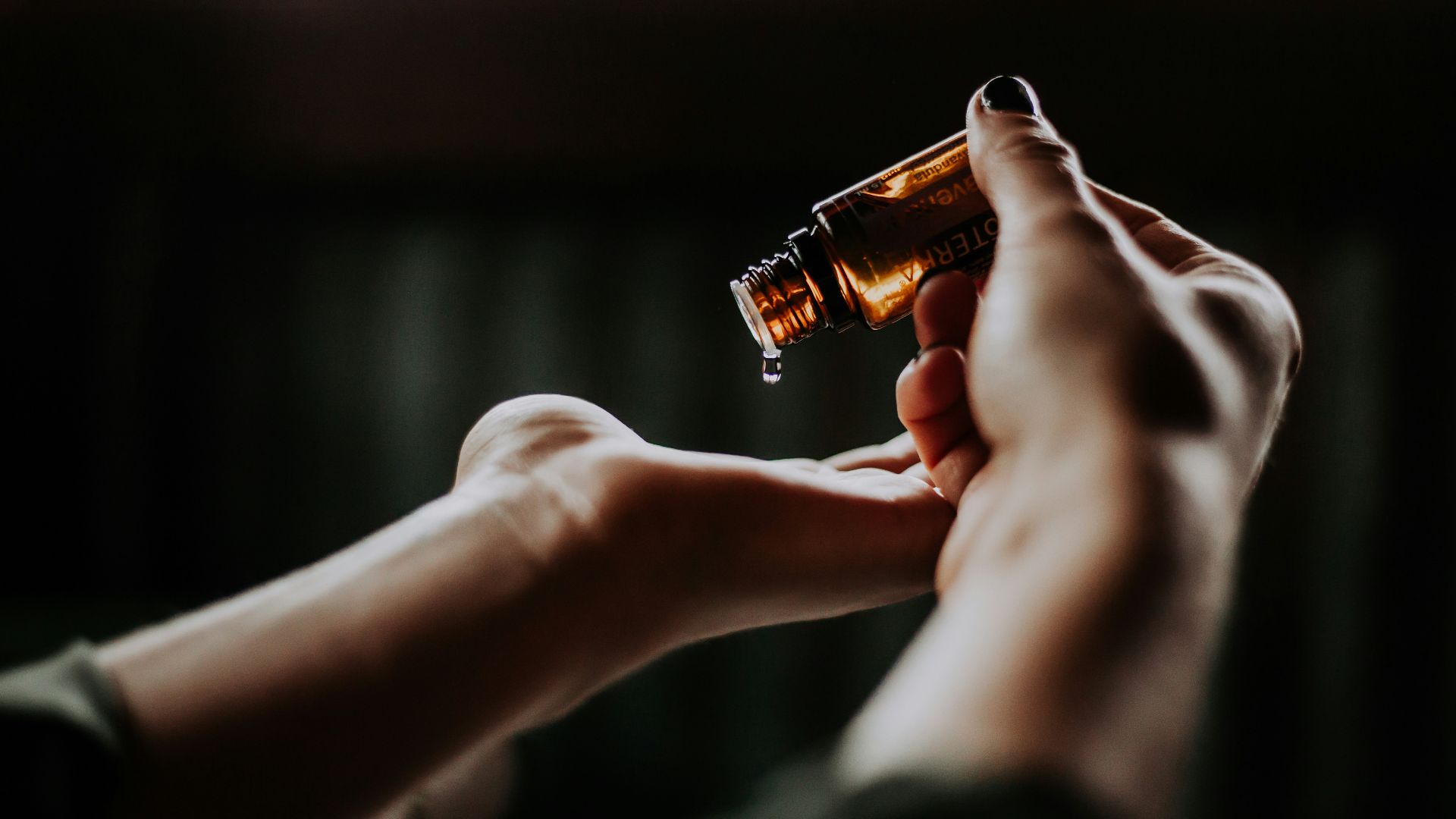 person holding amber glass bottle