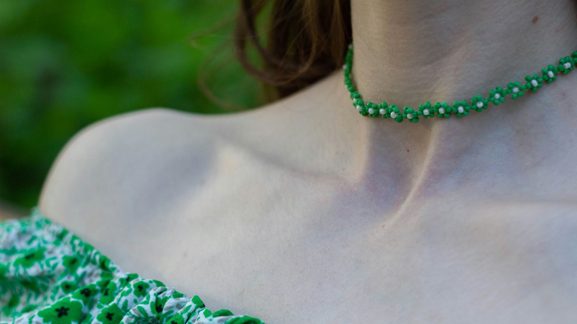 a close up of a woman wearing a green necklace