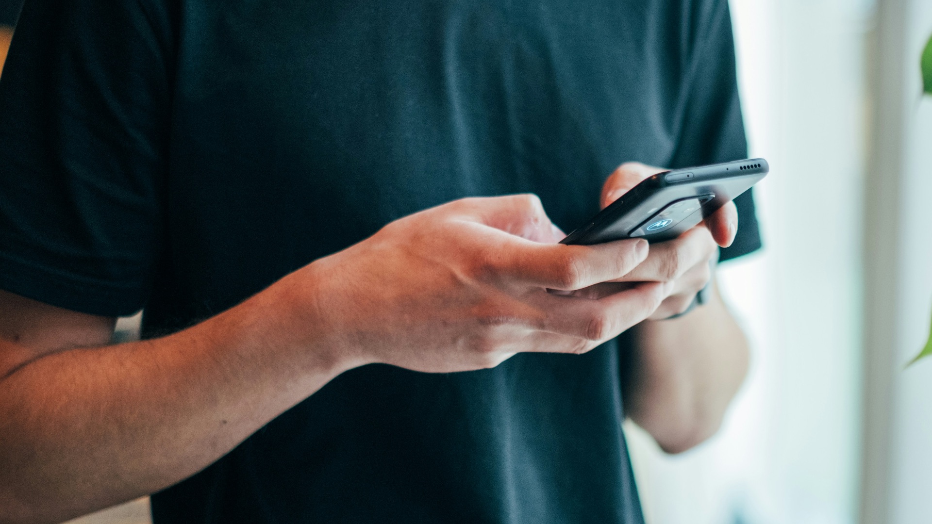 man in black crew-neck top using smartphone