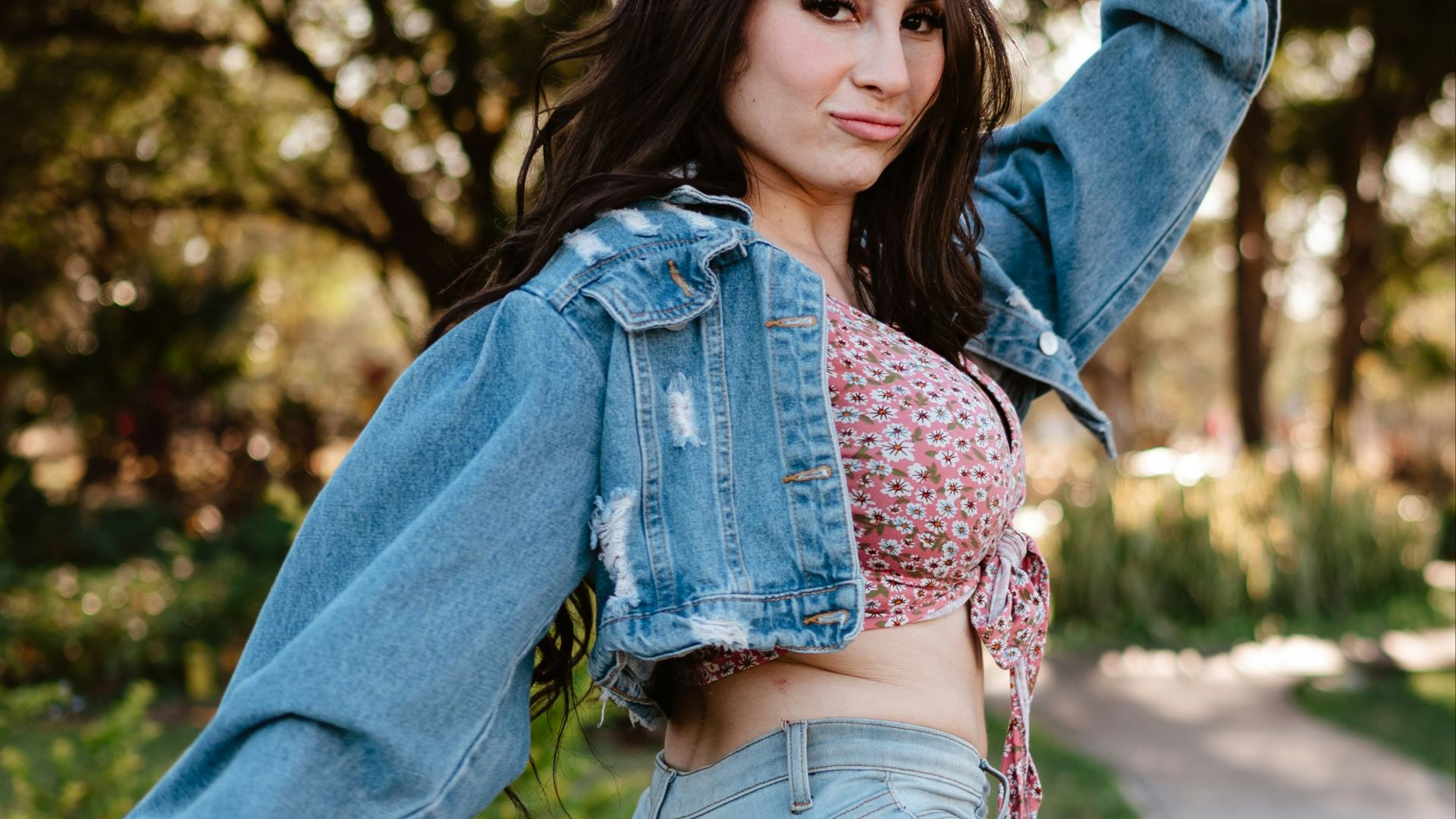 Woman in denim jacket and jeans posing outdoors