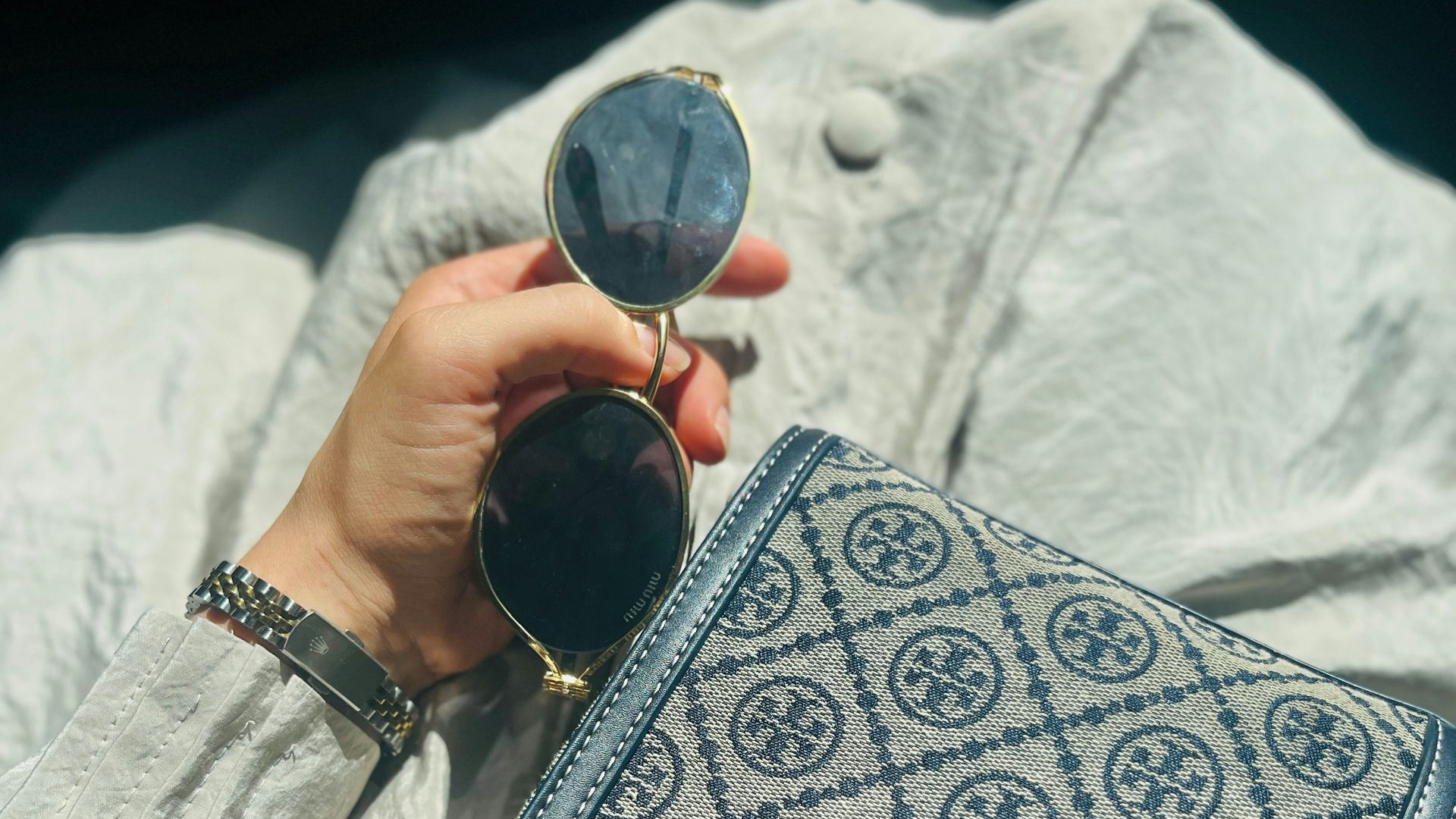 Woman holding sunglasses and patterned handbag