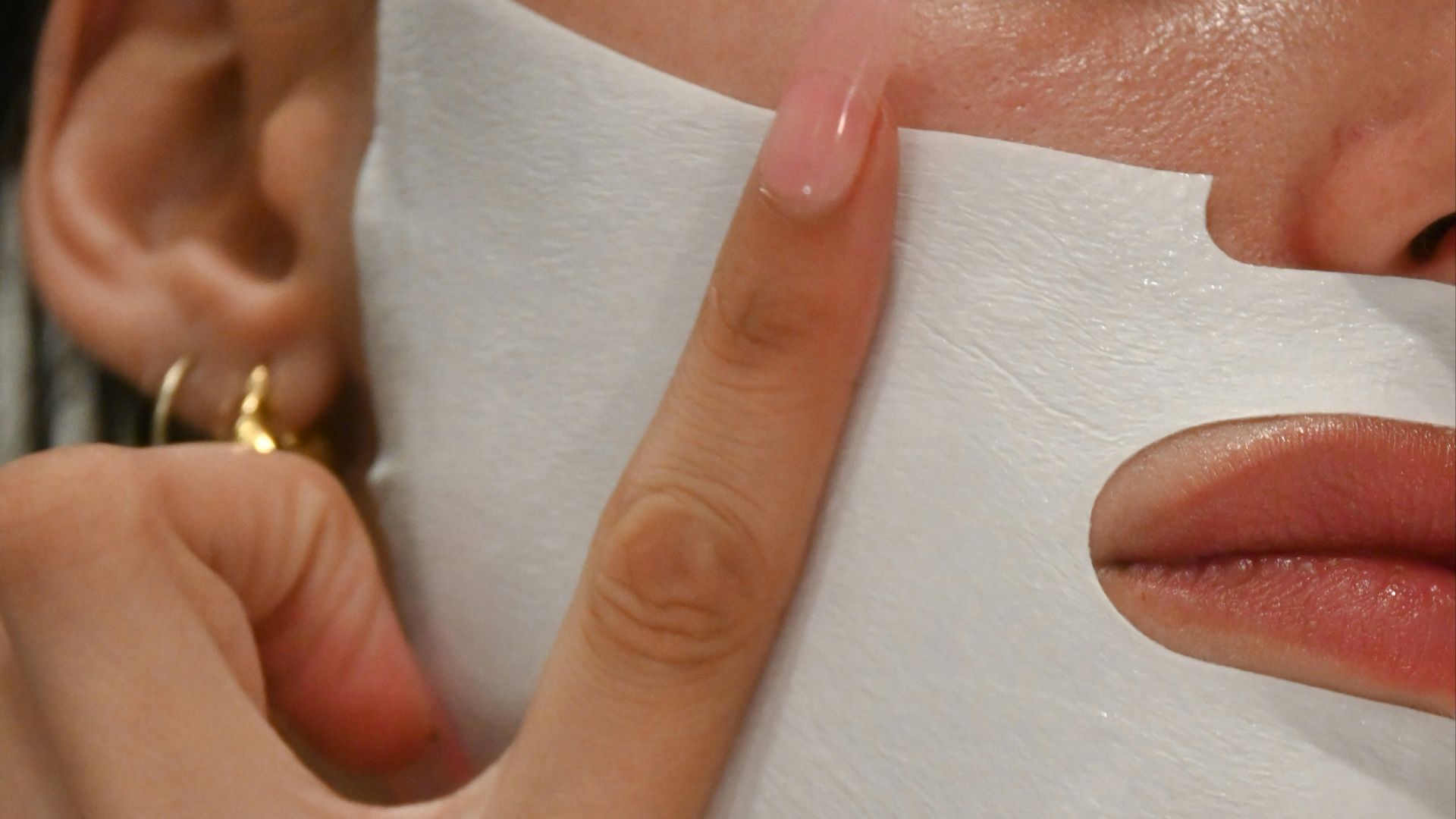 a woman putting a sheet of paper on her face