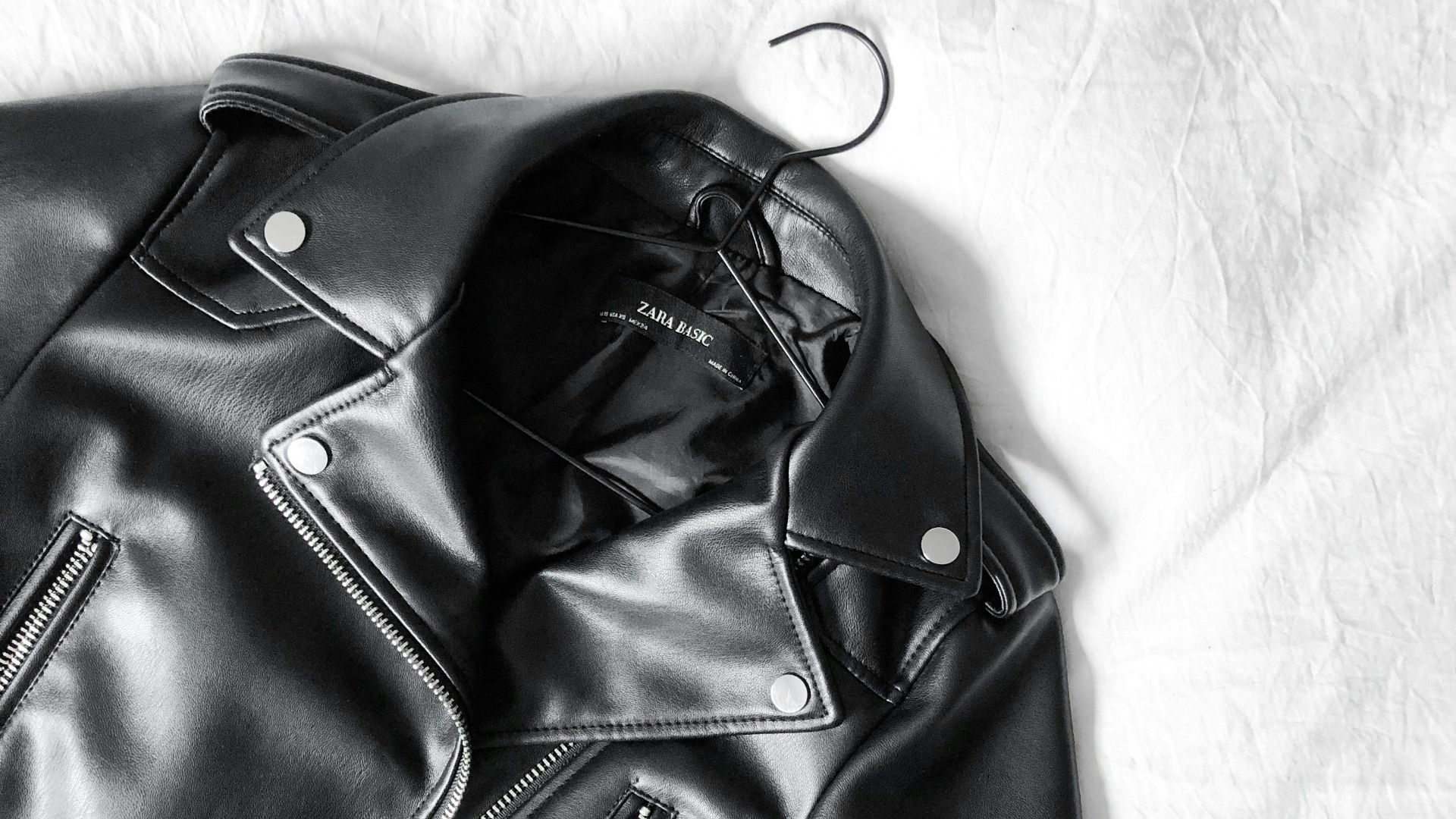 black leather zip-up jacket on white textile