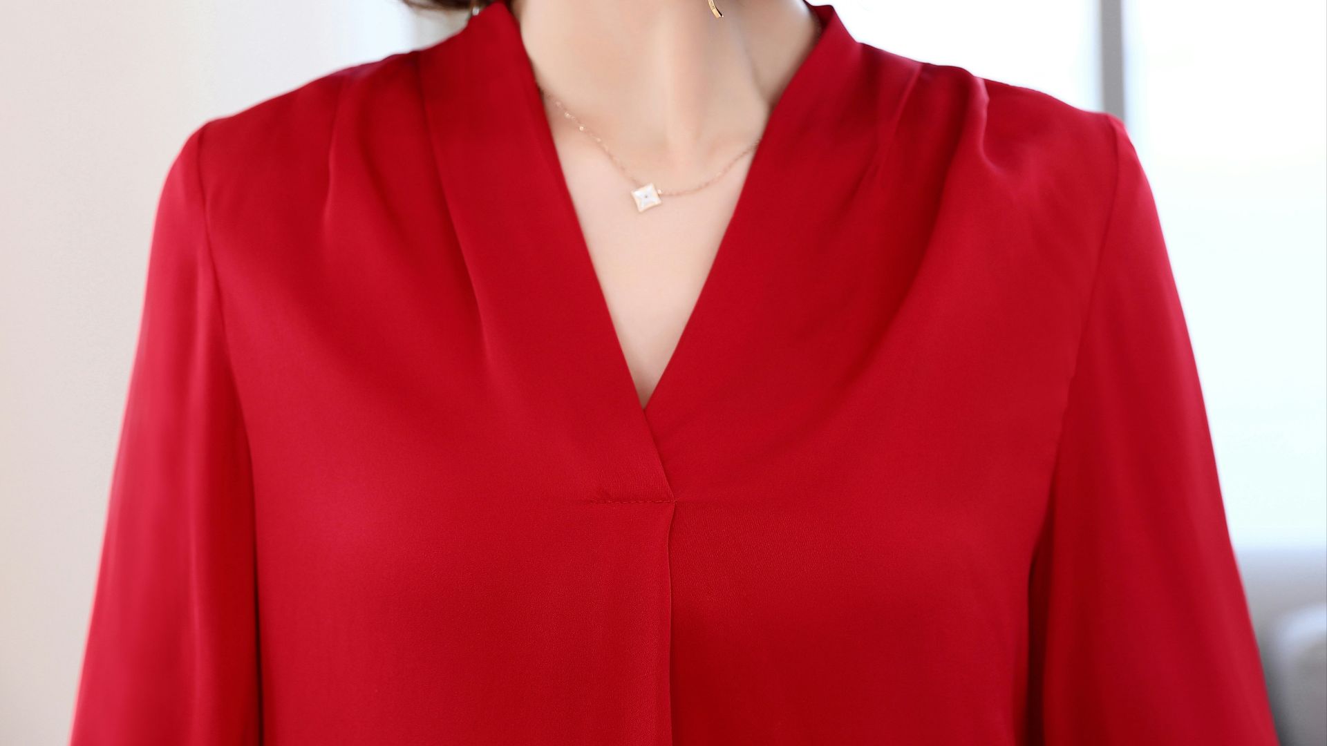 A woman in a red blouse with a necklace.