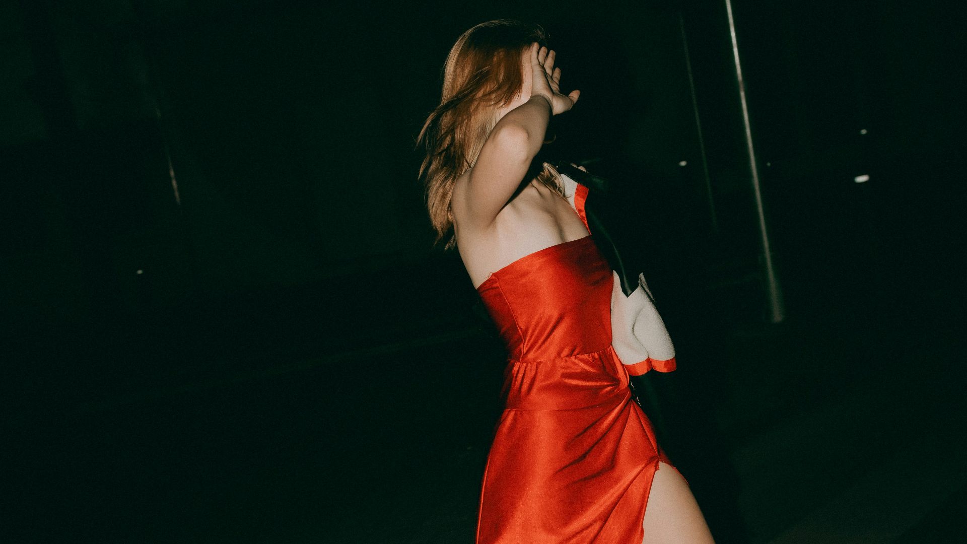 Woman in red dress walks at night.