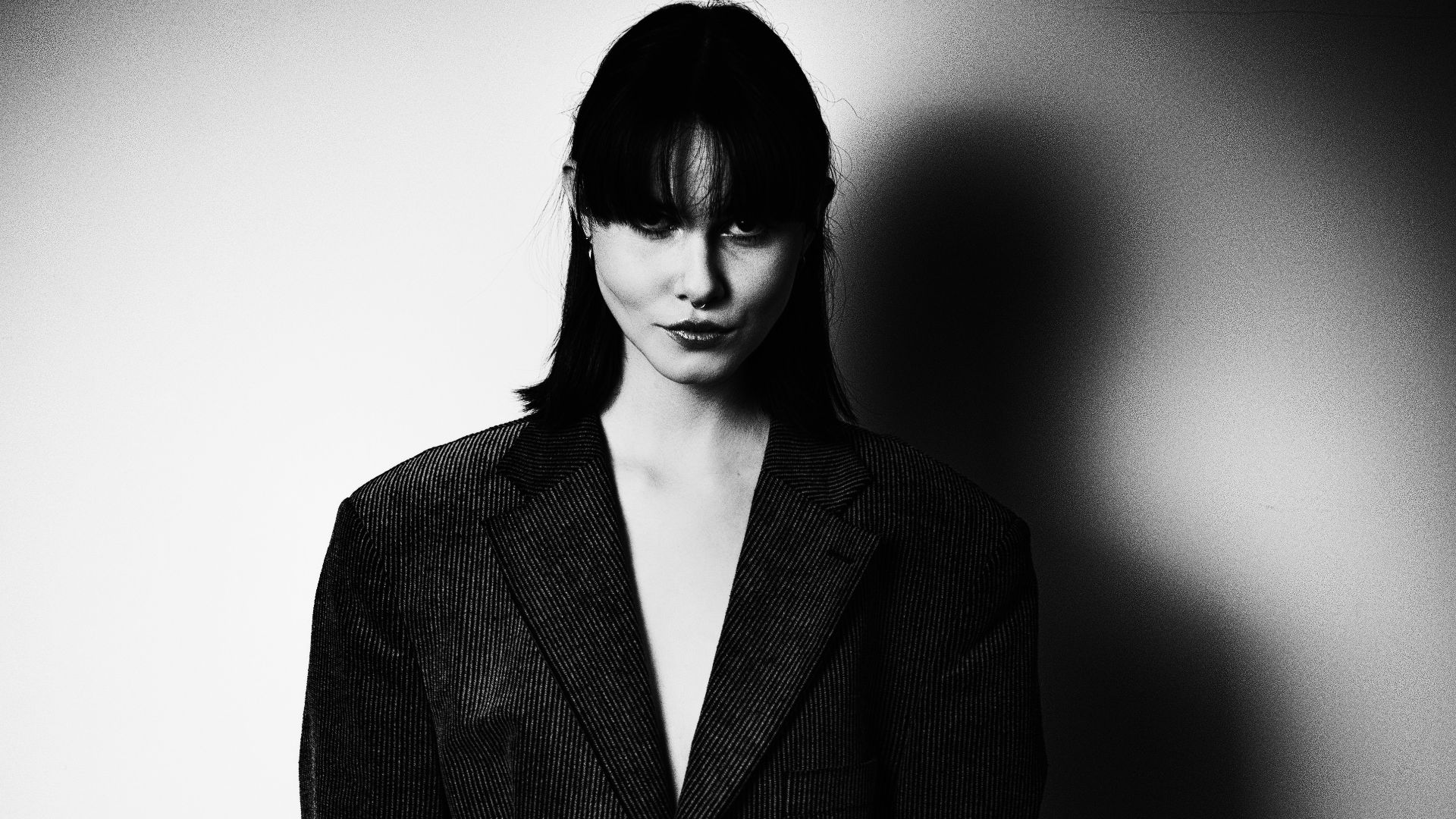 Woman in oversized blazer against a spotlighted wall