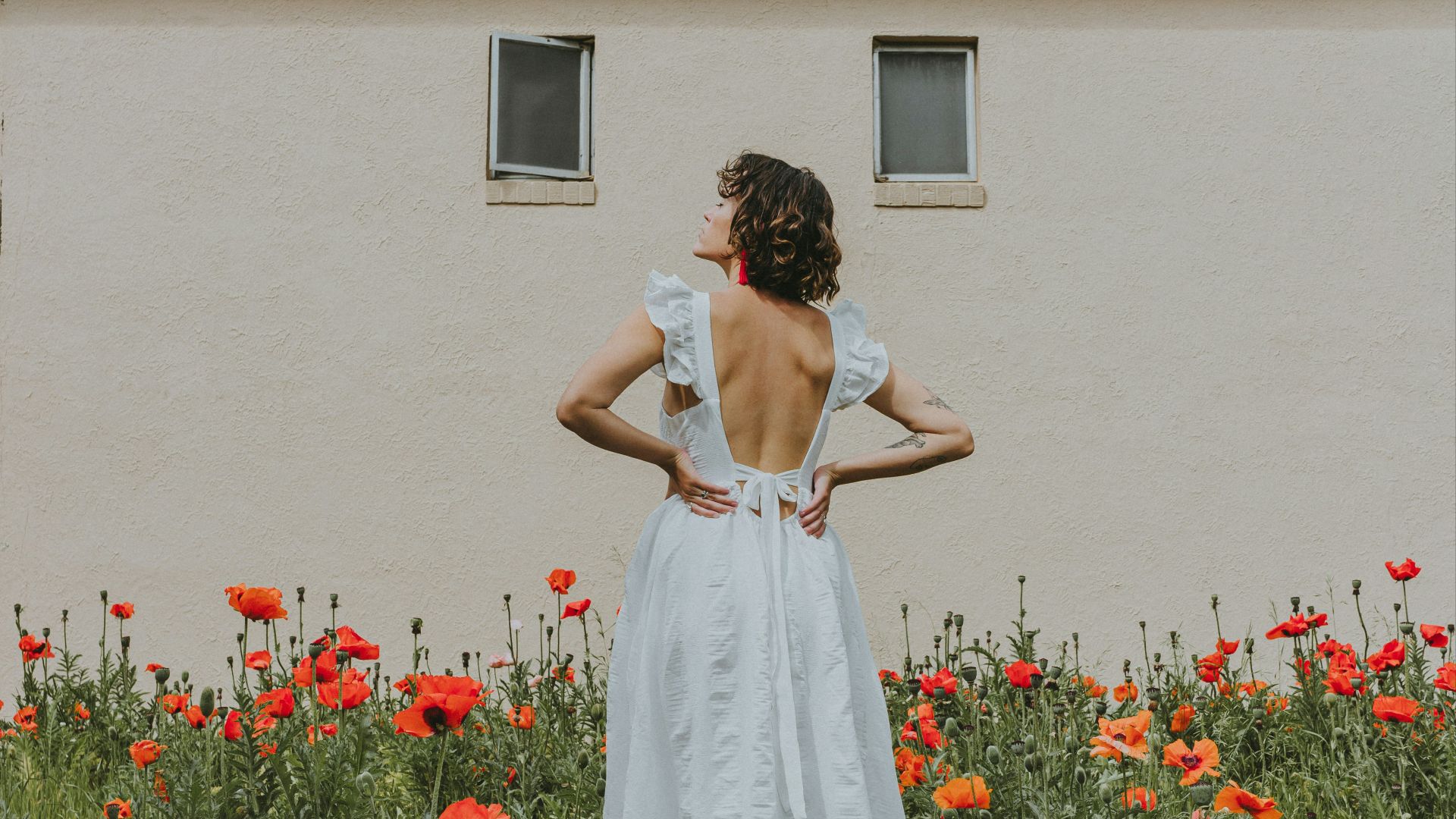 woman in white dress standing on red flower field during daytime