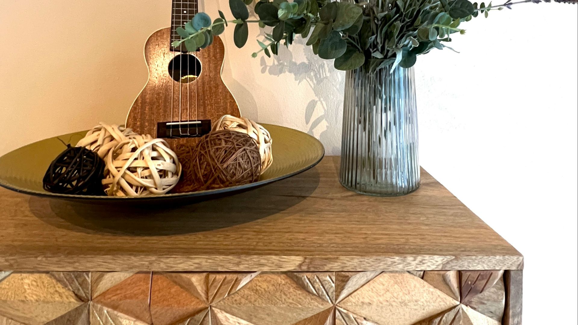 a wooden table topped with a guitar and a vase filled with flowers
