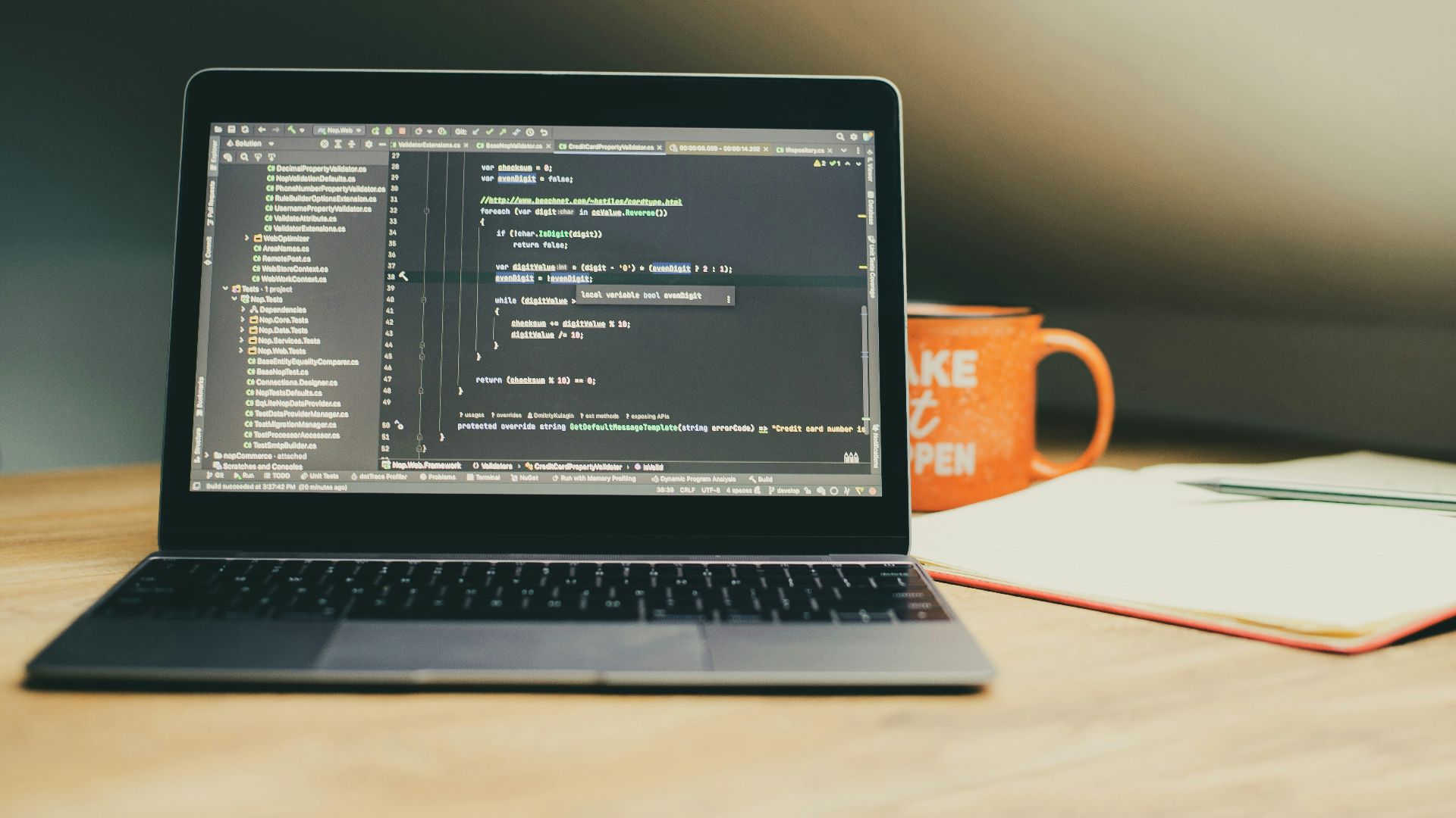 Laptop displaying code with an orange mug nearby