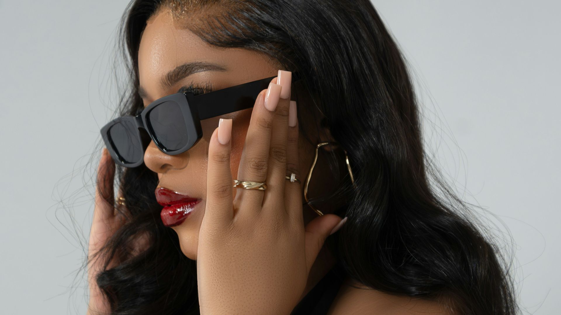 A woman in a black dress holding a pair of sunglasses