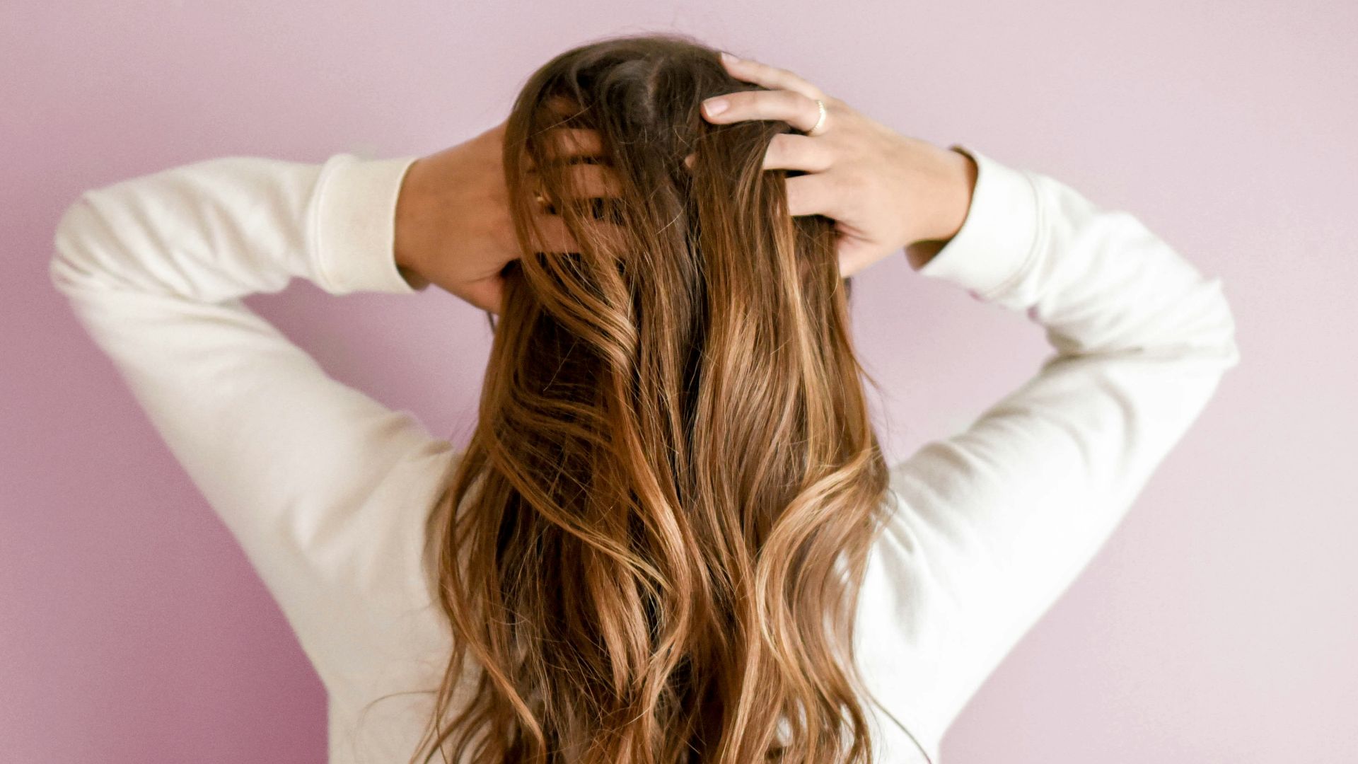 woman in white long-sleeved shirt standing in front of pink wall