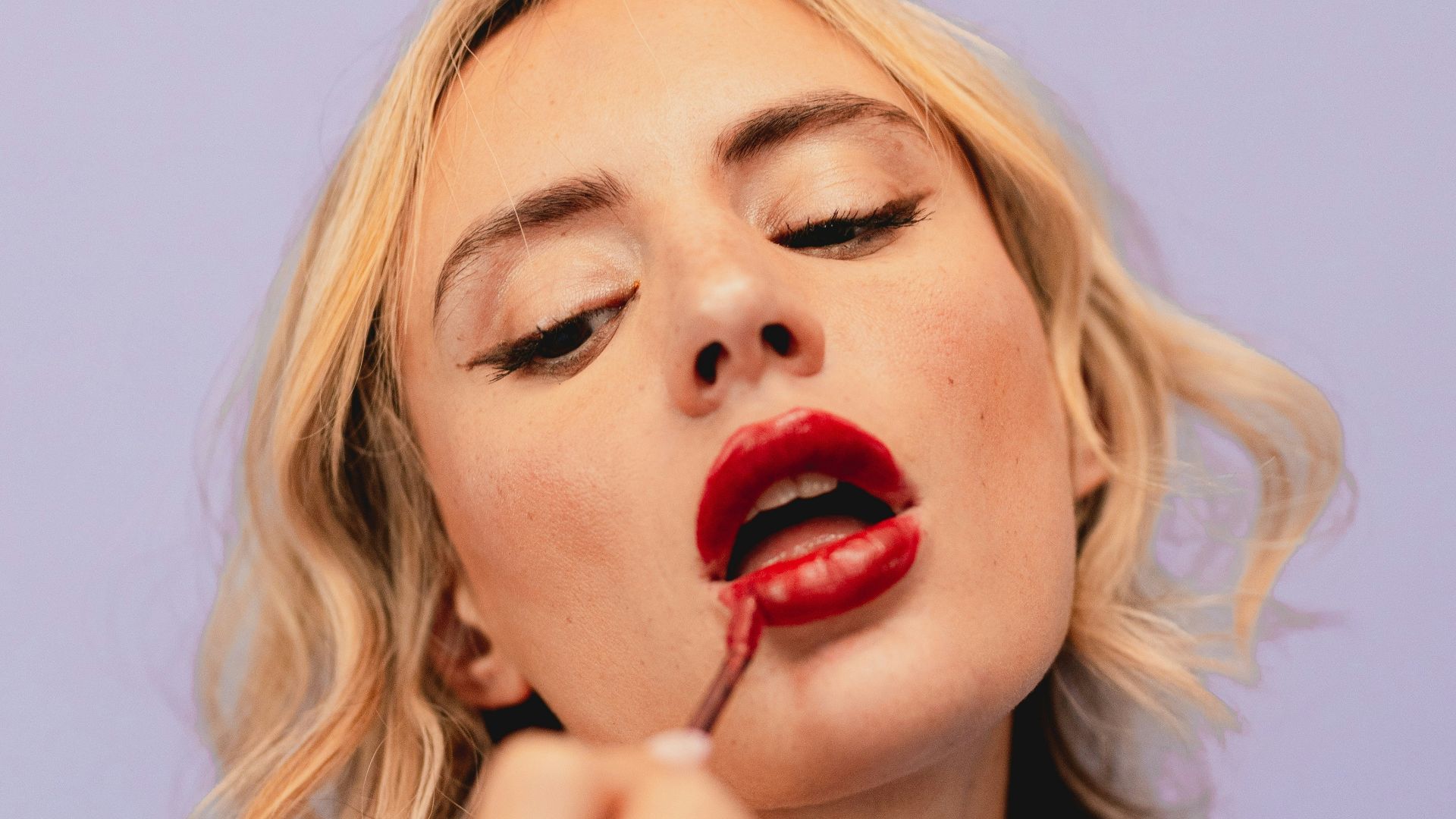 a woman putting lipstick on her lips