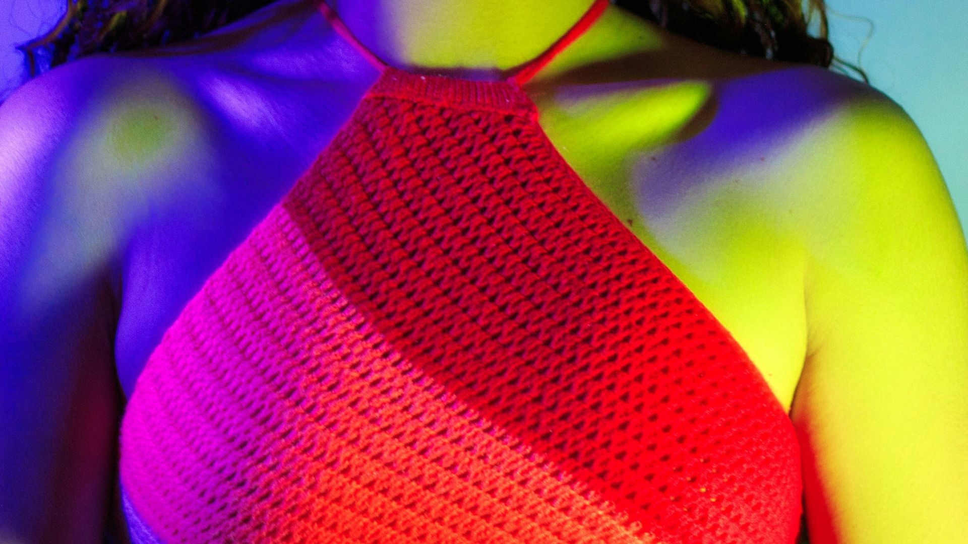 Woman with braided hair wearing red top with colorful lighting