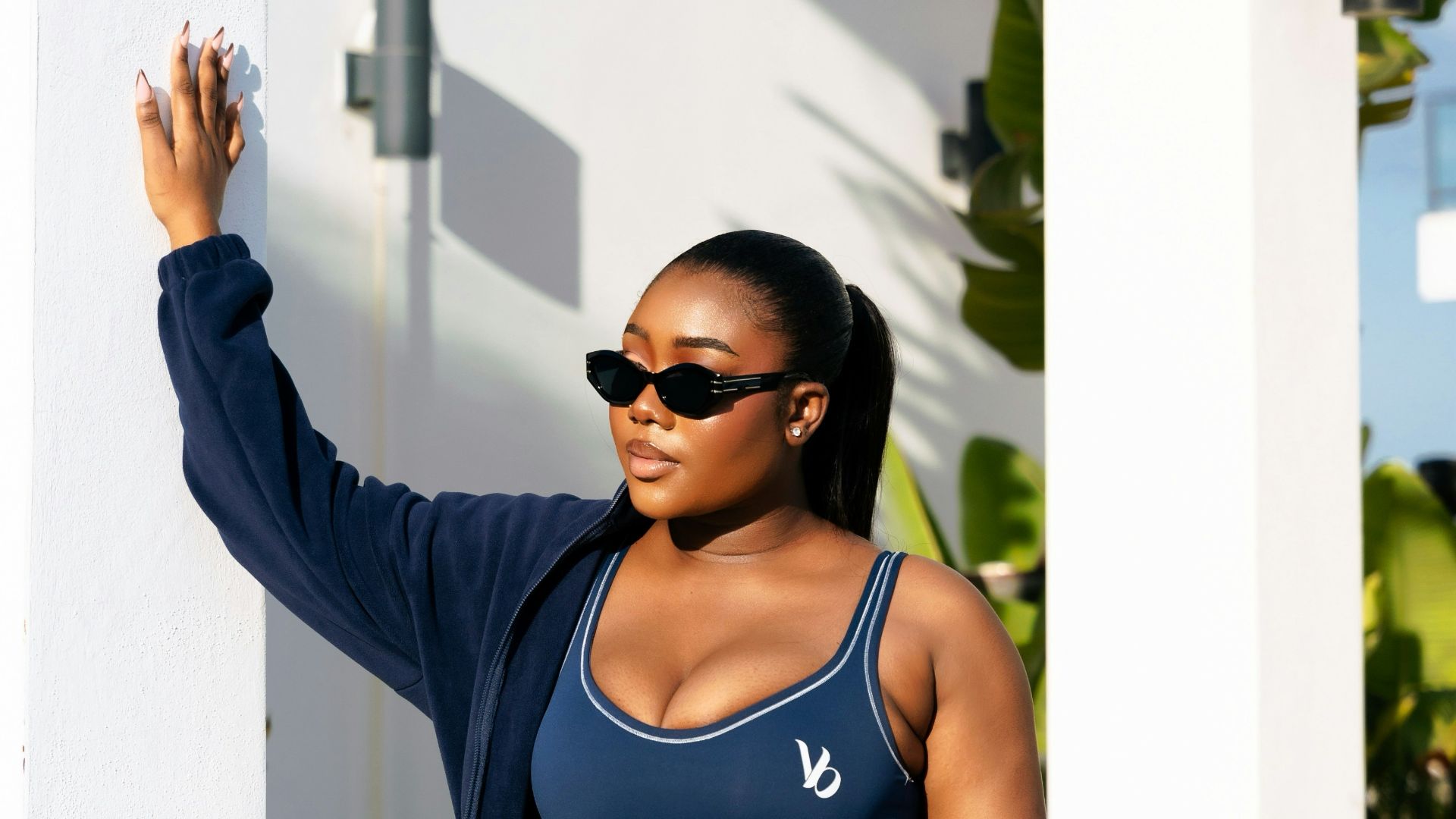 A woman in navy activewear holds a pink gym bag.