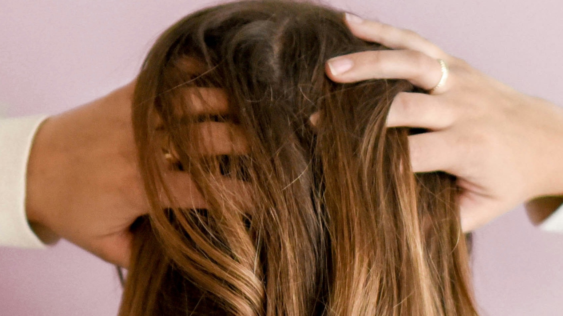 woman in white long-sleeved shirt standing in front of pink wall