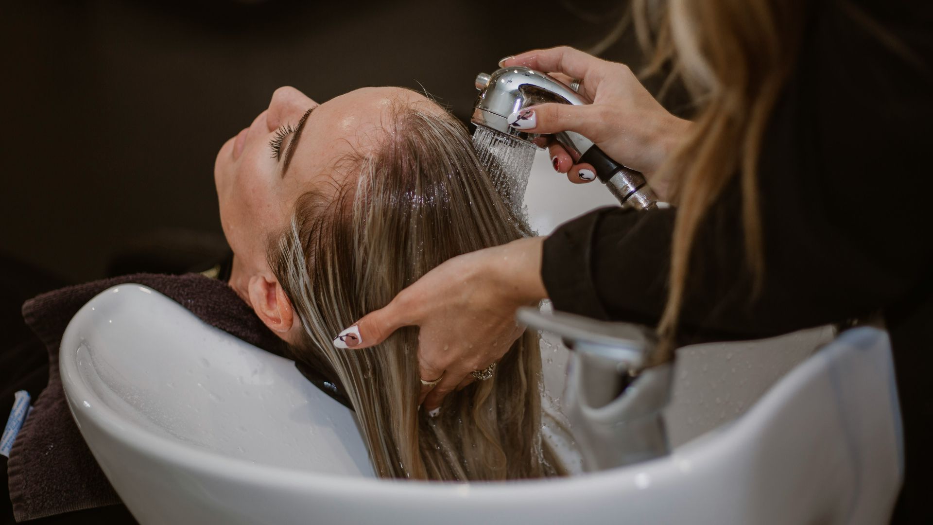 a woman getting her hair cut by a hair stylist