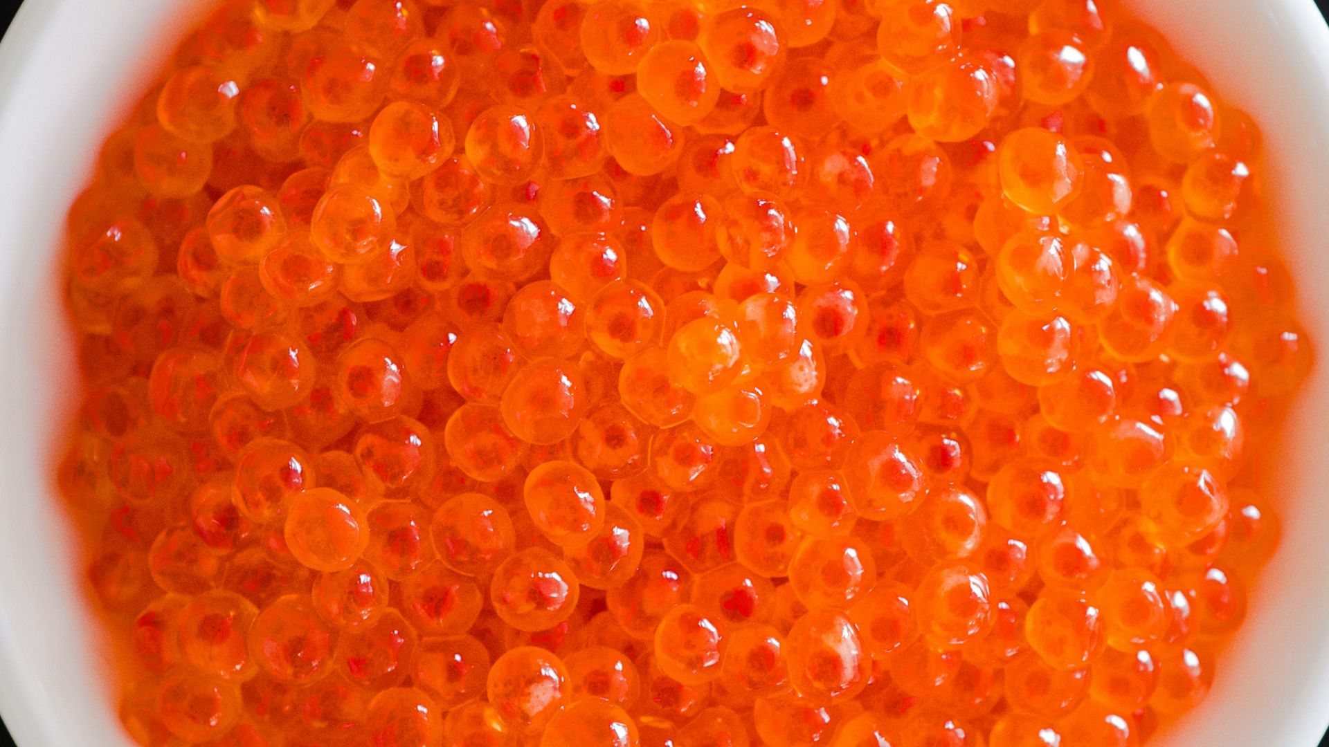 A white bowl filled with red cavia on top of a table