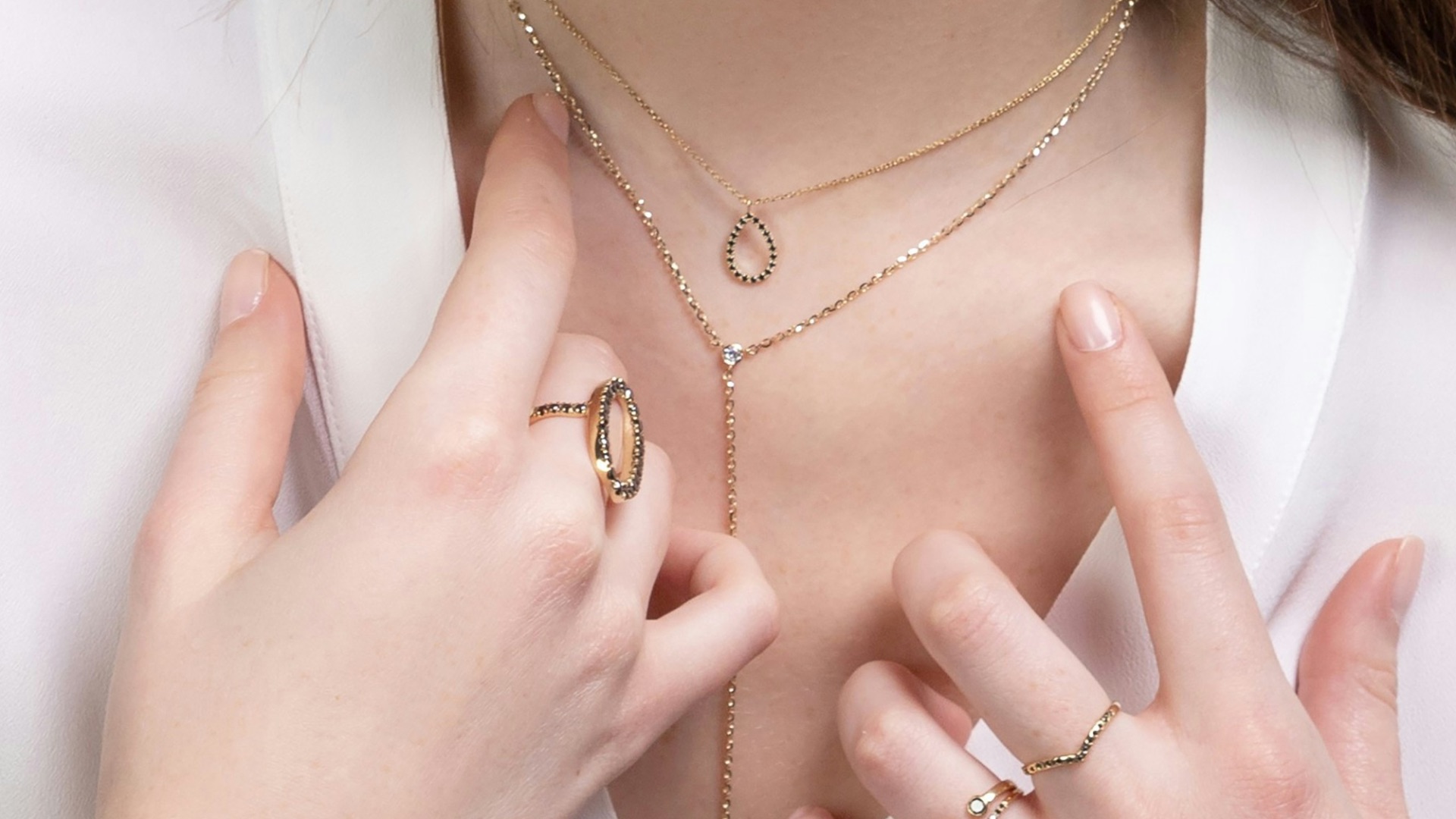 a close up of a person wearing rings and a necklace