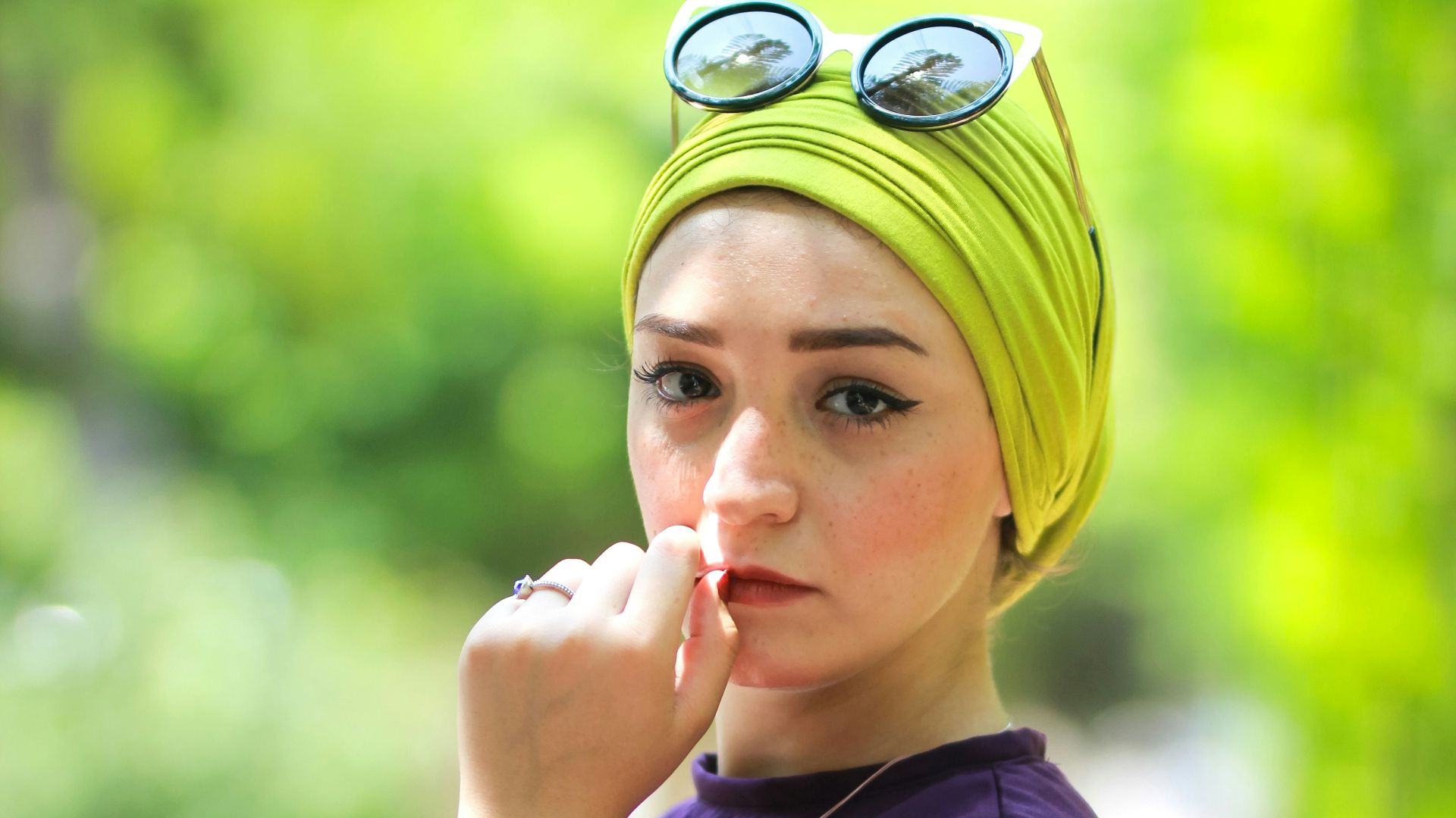 woman wearing purple long-sleeved top holding her lips during daytime
