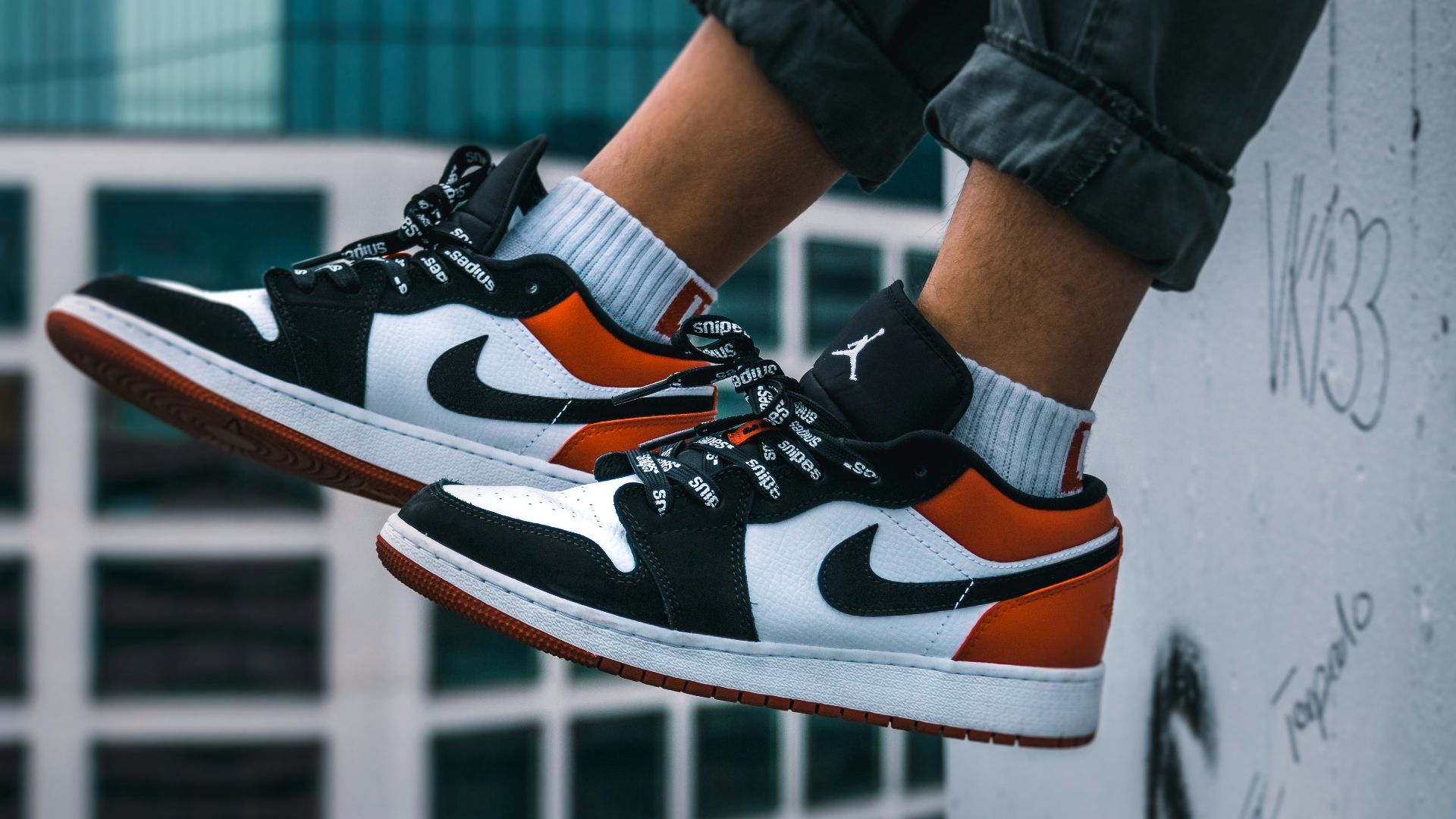 man sitting on the ledge of a building wearing Air Jordan 1 low-top shoes
