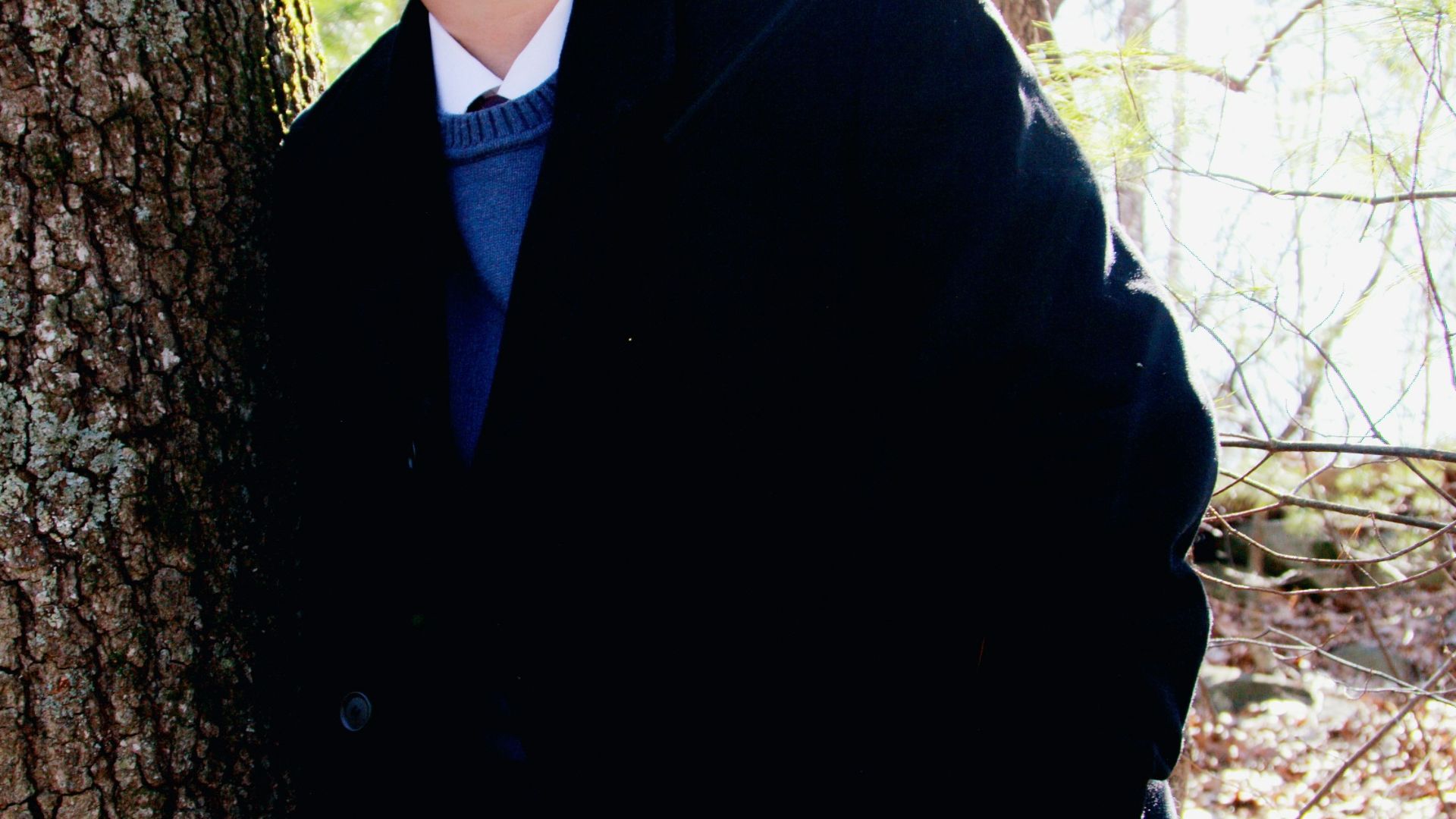 man in black coat and blue denim jeans sitting on tree