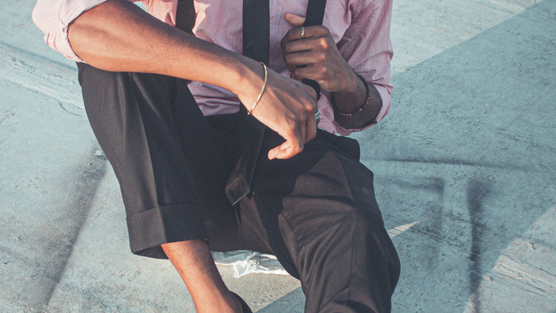 Young man in stylish outfit sitting outdoors