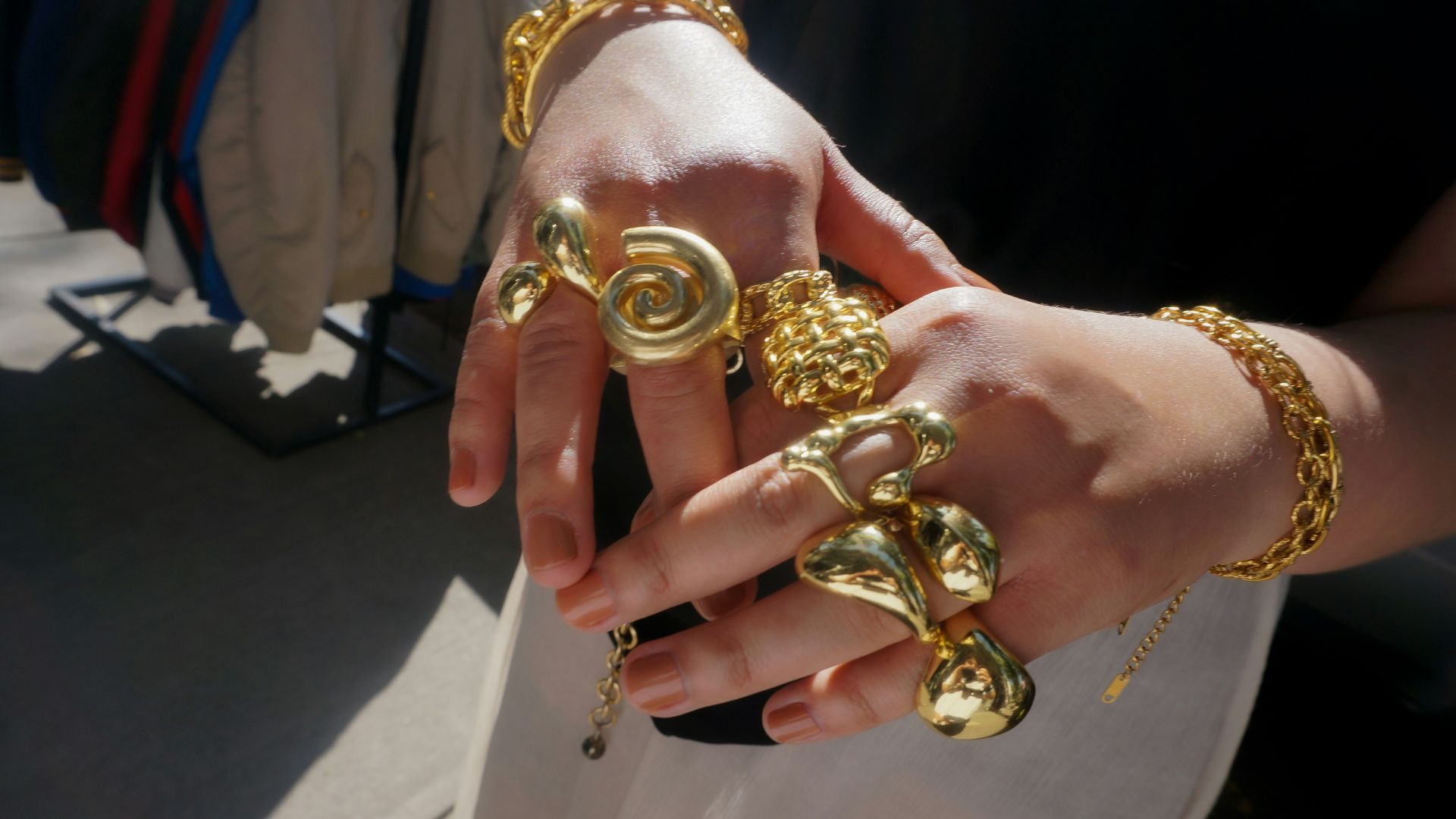 Hands adorned with chunky gold rings and bracelets.