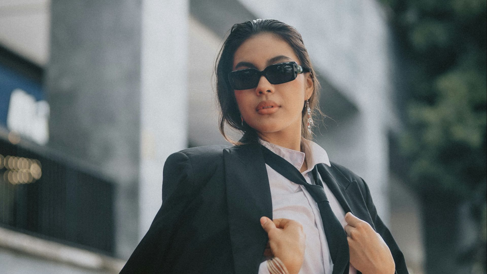A woman in a suit and sunglasses is walking down the street