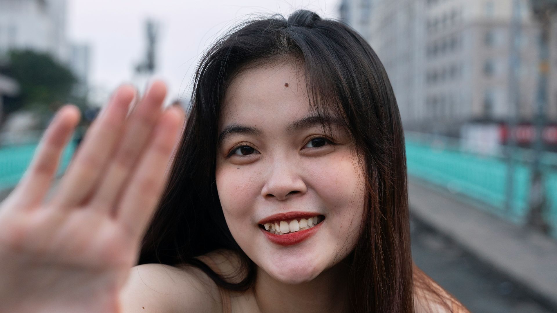 a woman is smiling and waving her hand