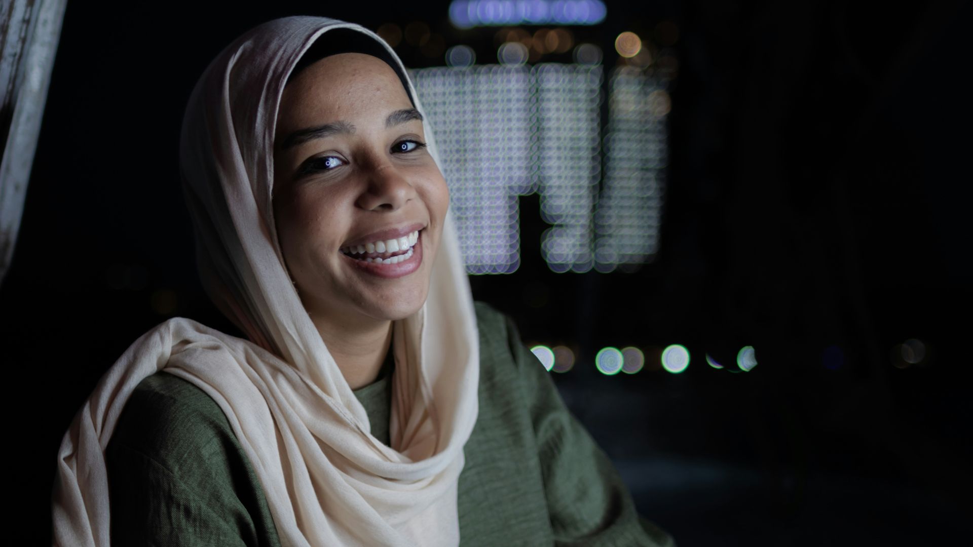 a woman in a headscarf smiles at the camera